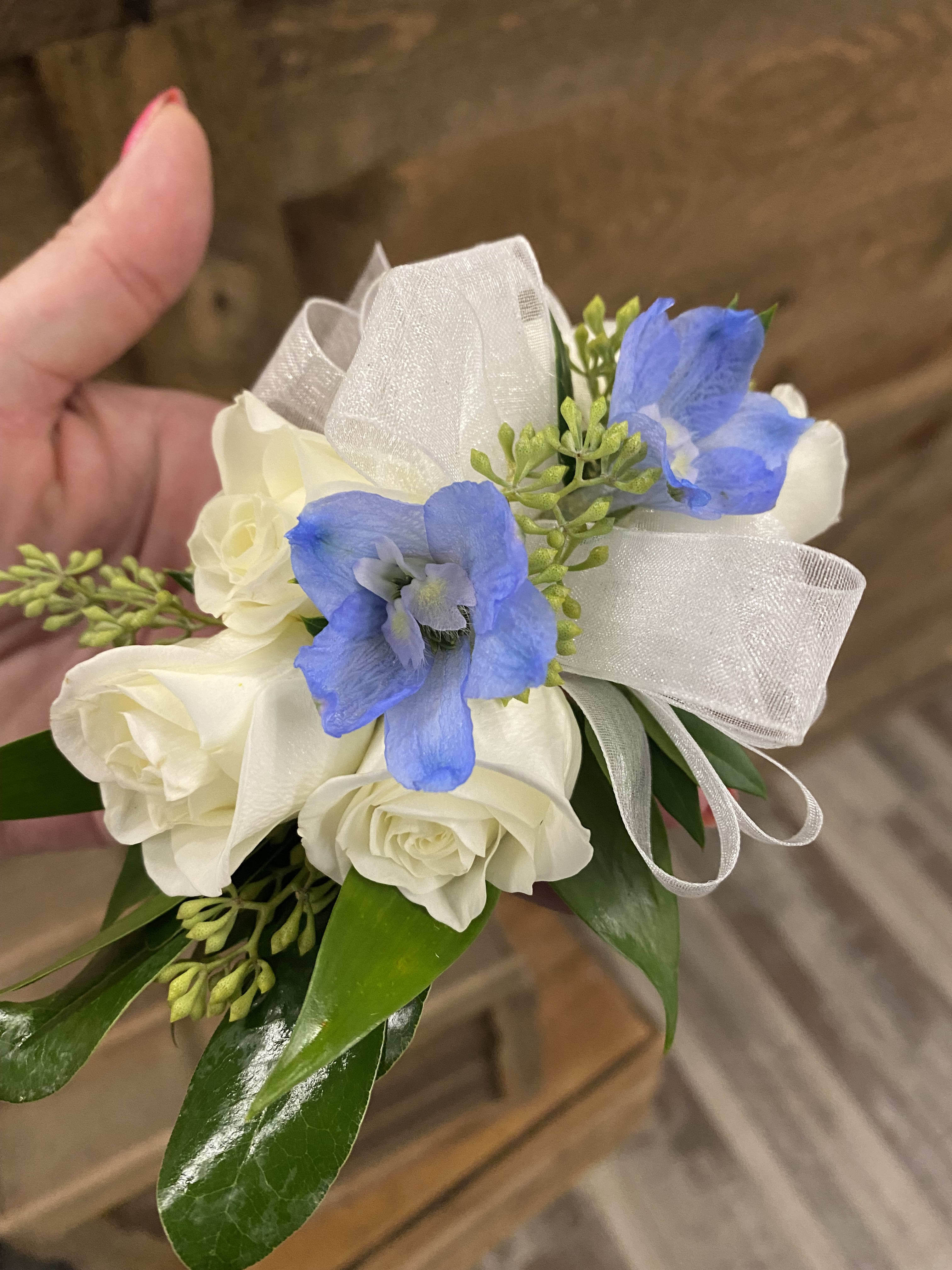 Small bouquet of white roses and blue flowers with a sheer ribbon