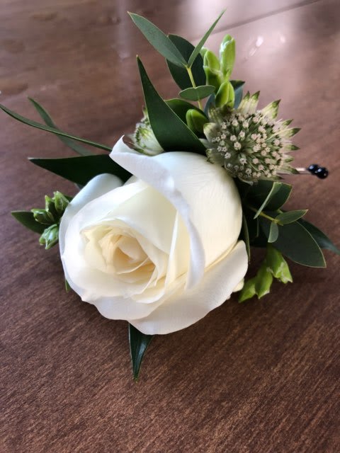 White rose boutonniere with green foliage and small filler flowers