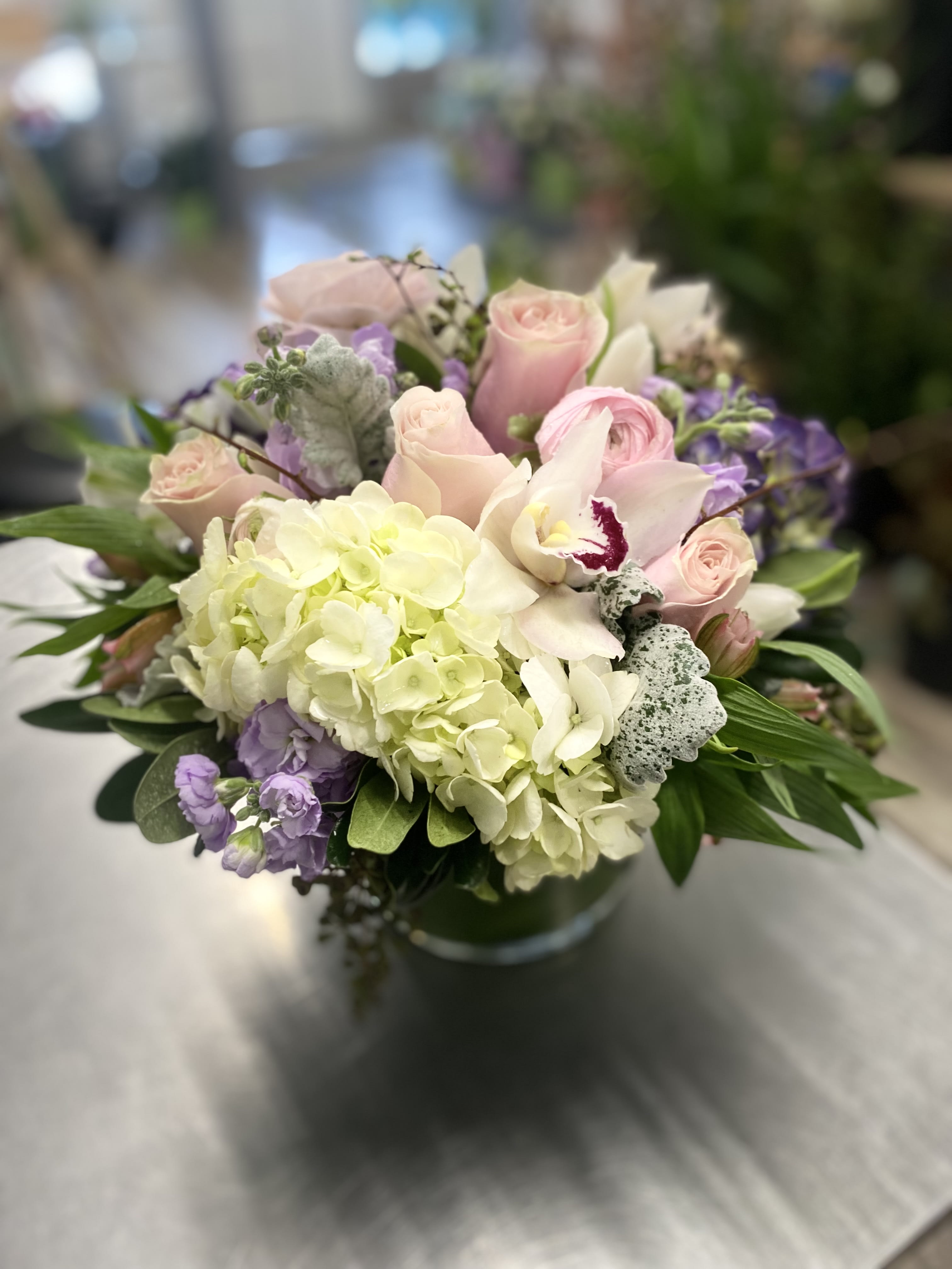 Bouquet of pale pink roses, white hydrangea, and purple flowers in a vase