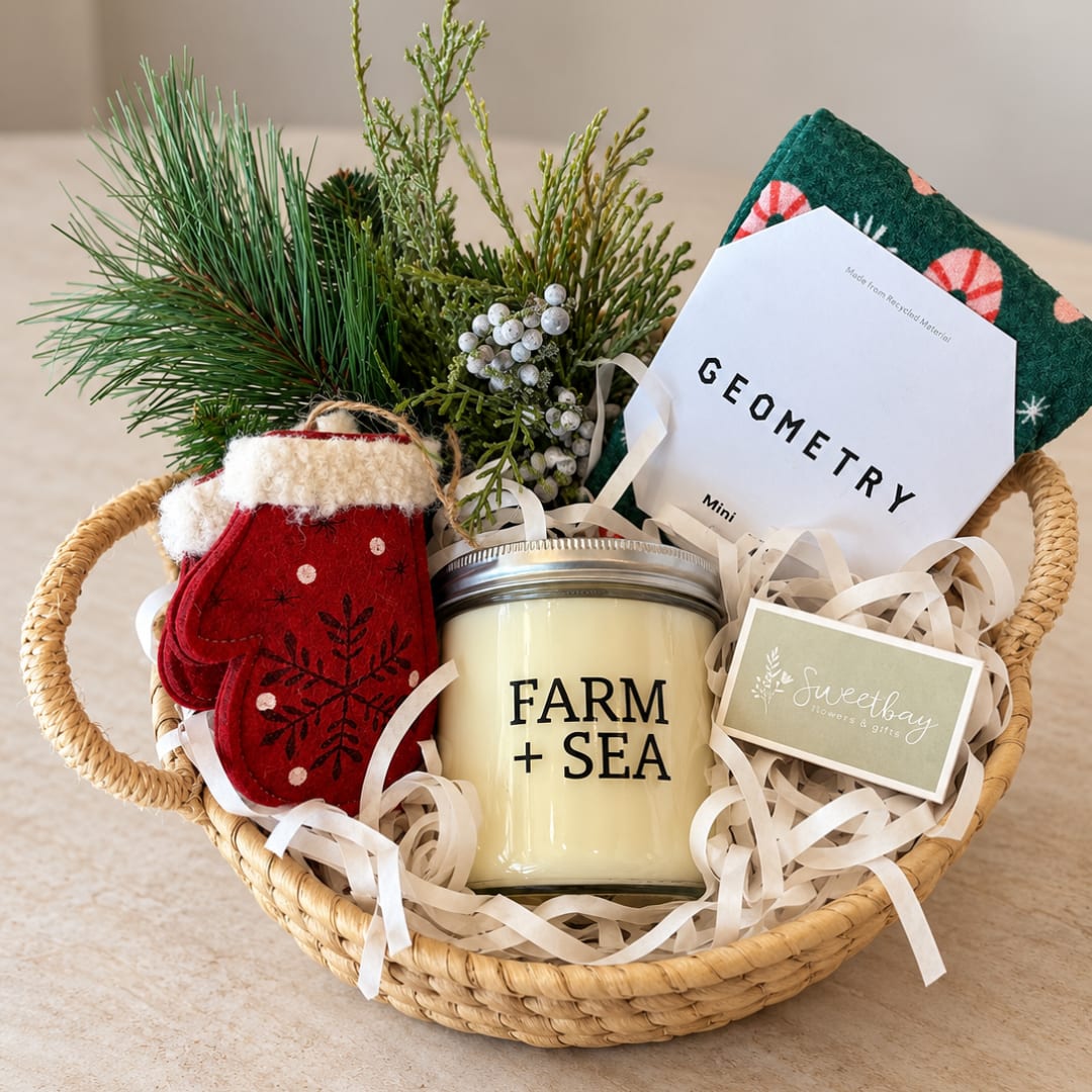 Holiday gift basket with a candle, mittens, and a small evergreen bundle