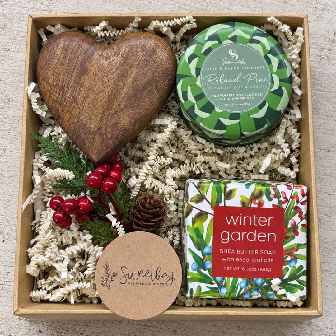 Gift box with a wooden heart, candle, soap, and holiday greenery accents