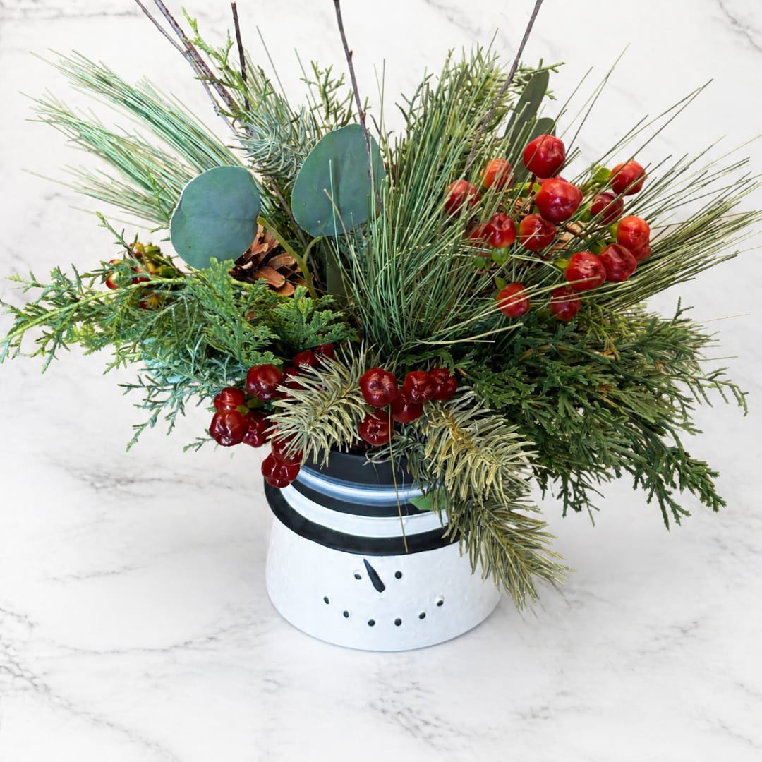 Holiday arrangement in a snowman pot with pine, berries, and eucalyptus