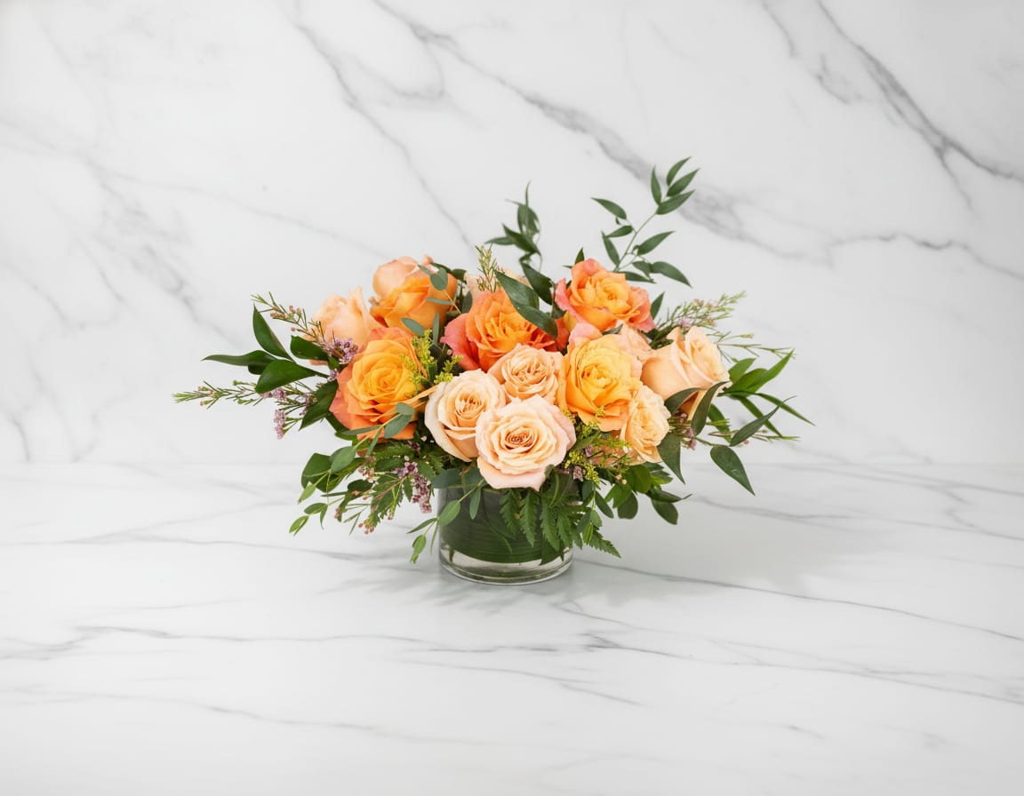 Apricot Glow - Radiating warmth and effortless beauty, Summer Glow features a luminous blend of orange and apricot-hued roses, accented with seasonal textures and soft greenery. This vibrant arrangement captures the golden light of long summer days—cheerful, uplifting, and full of heartfelt charm. 