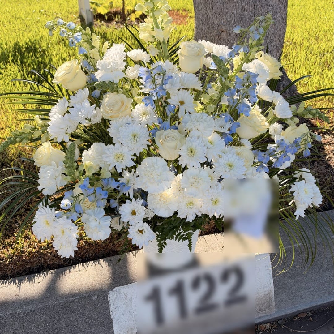 White roses and chrysanthemums with blue flowers in a cemetery vase arrangement