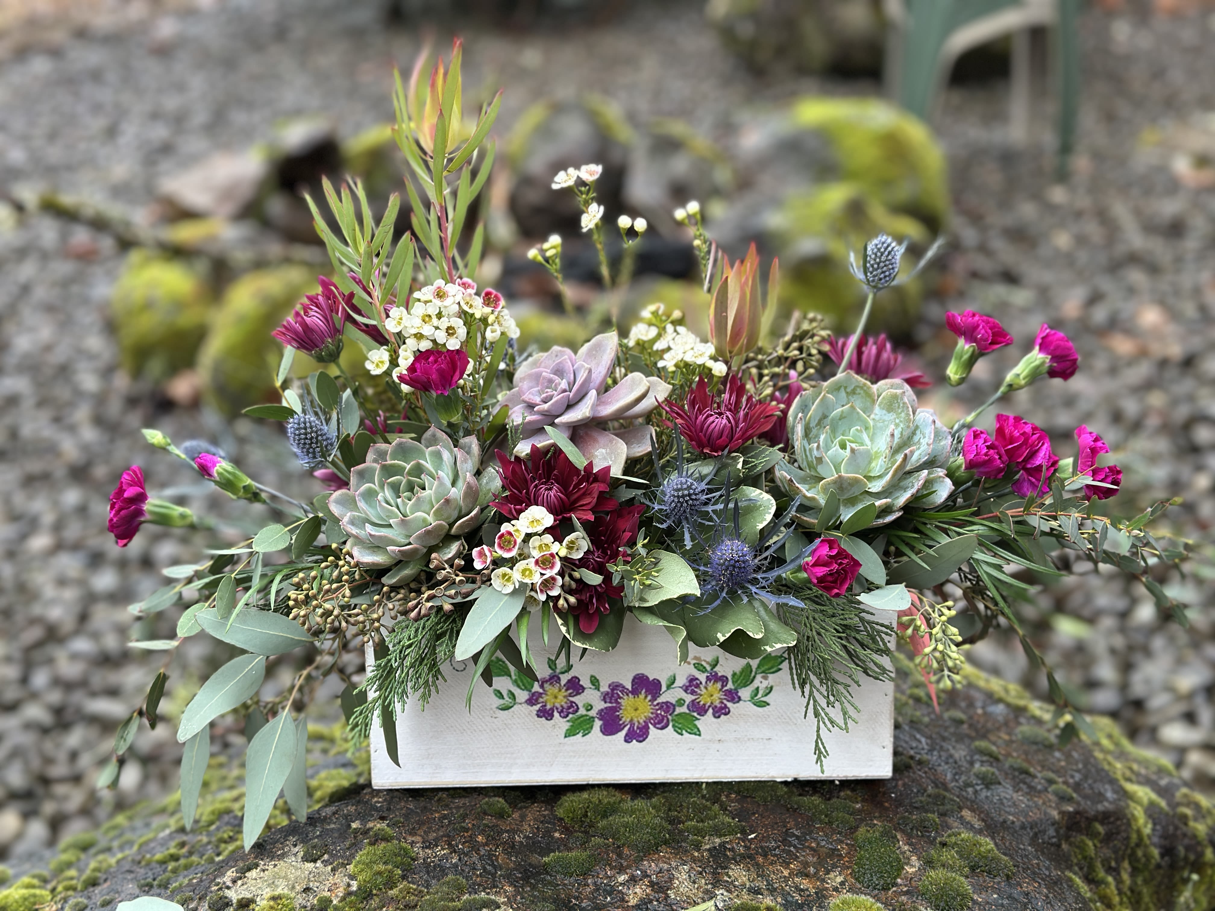 Succulent and magenta flower arrangement in a painted wooden box