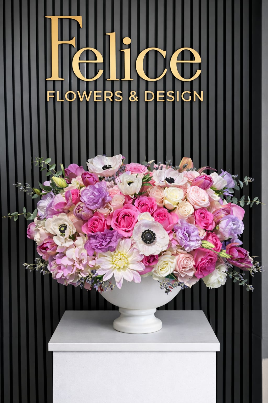 Large pink and lavender flower arrangement in a white pedestal vase