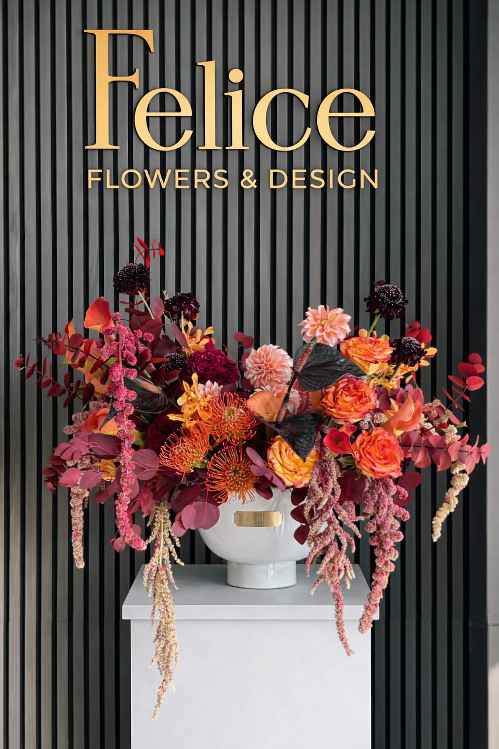 Large colorful floral arrangement in a white vase beneath a Felice Flowers &amp; Design sign