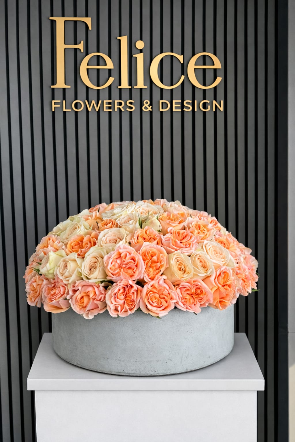 Large peach and cream rose arrangement in a round gray container