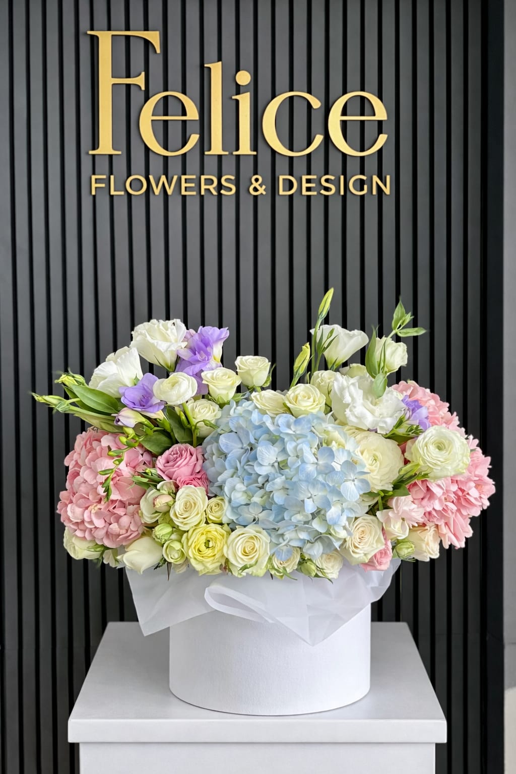 Pastel flower arrangement in a white hat box with hydrangeas and roses