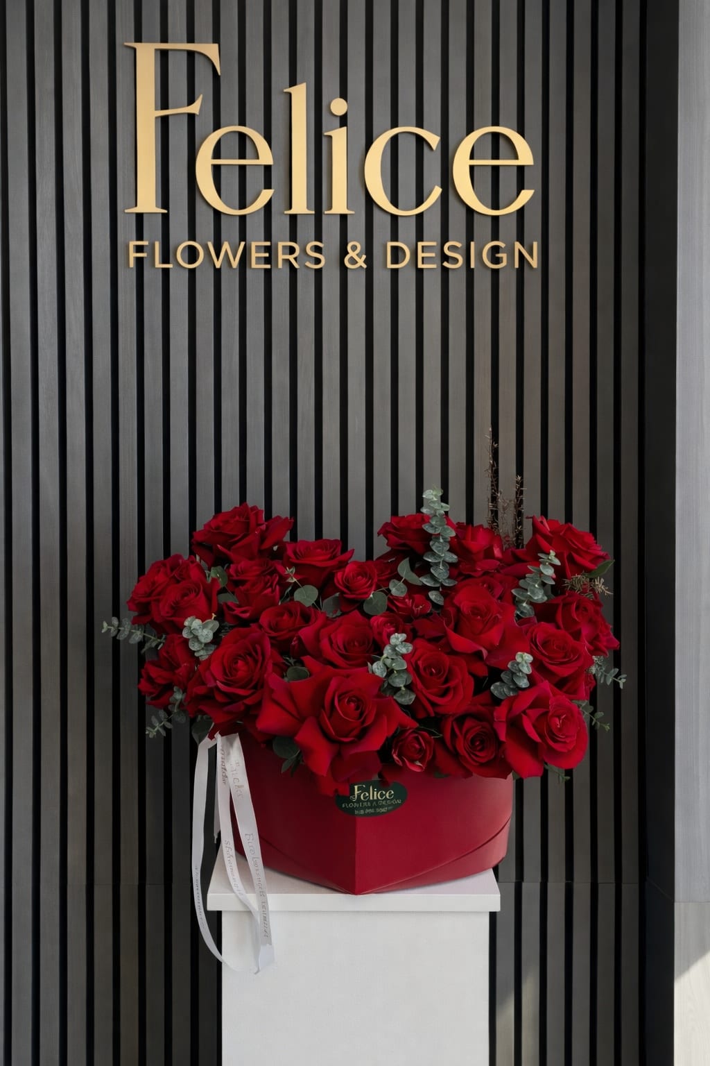 Red roses arranged in a heart-shaped box with ribbon accents