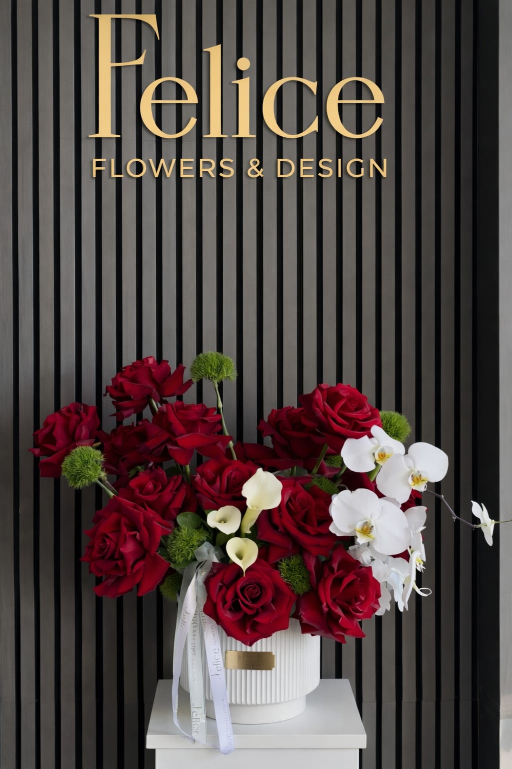 Red roses and white orchids arranged in a white vase