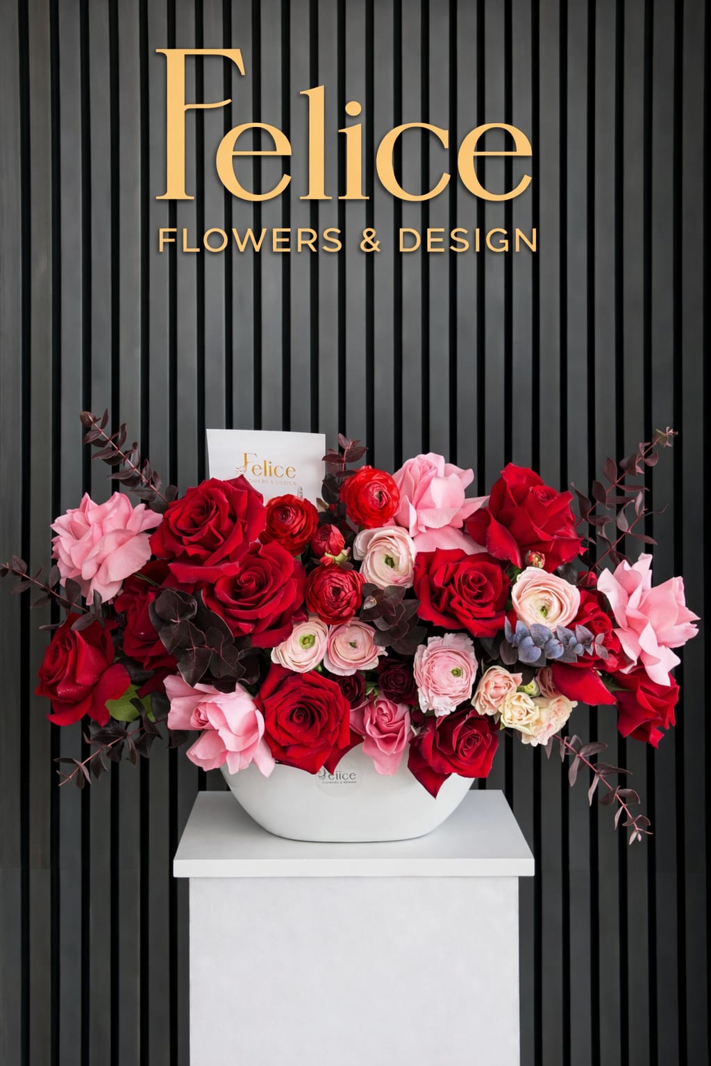 Red and pink rose arrangement in a white vase