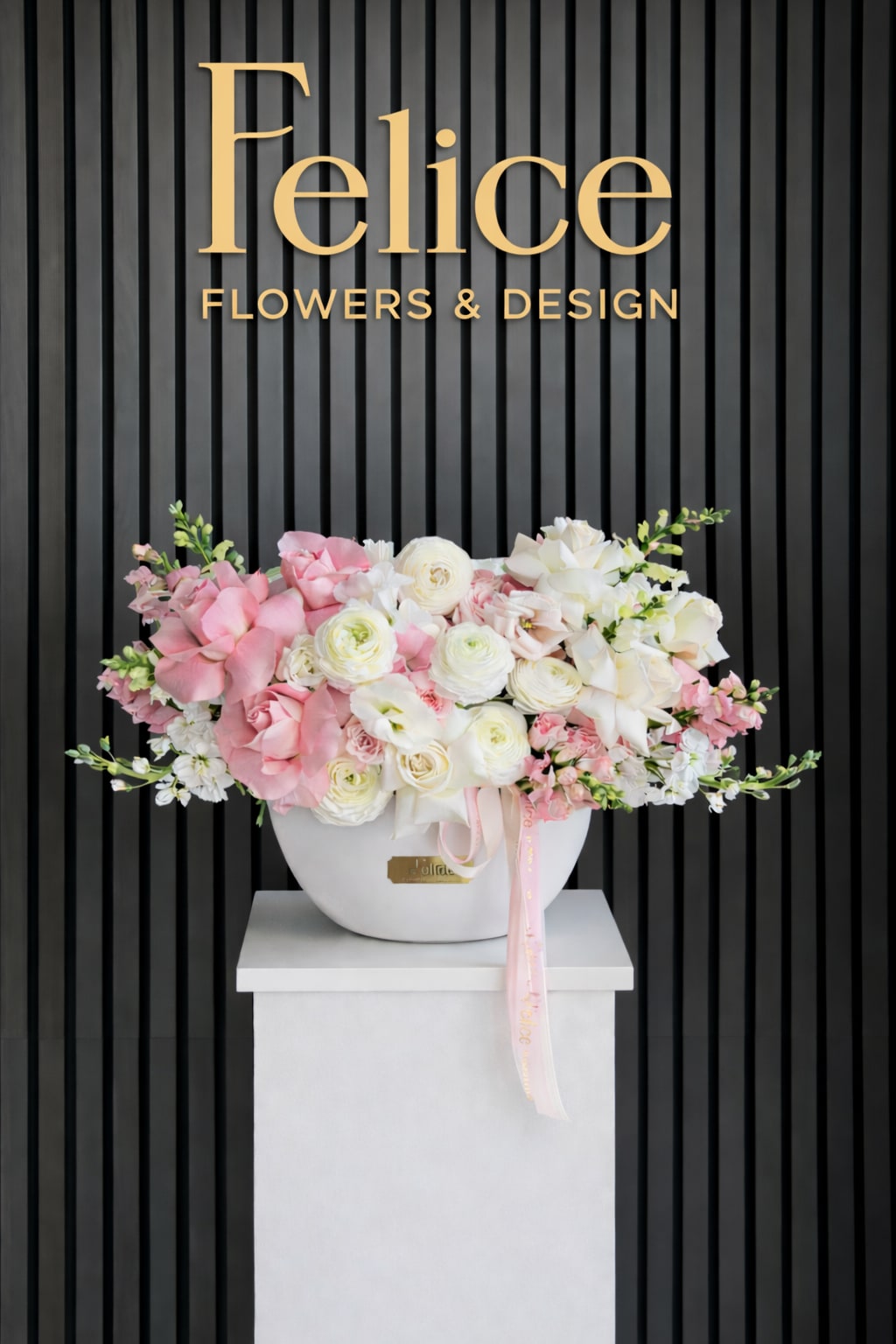 Pink and white floral arrangement in a white vase with a ribbon