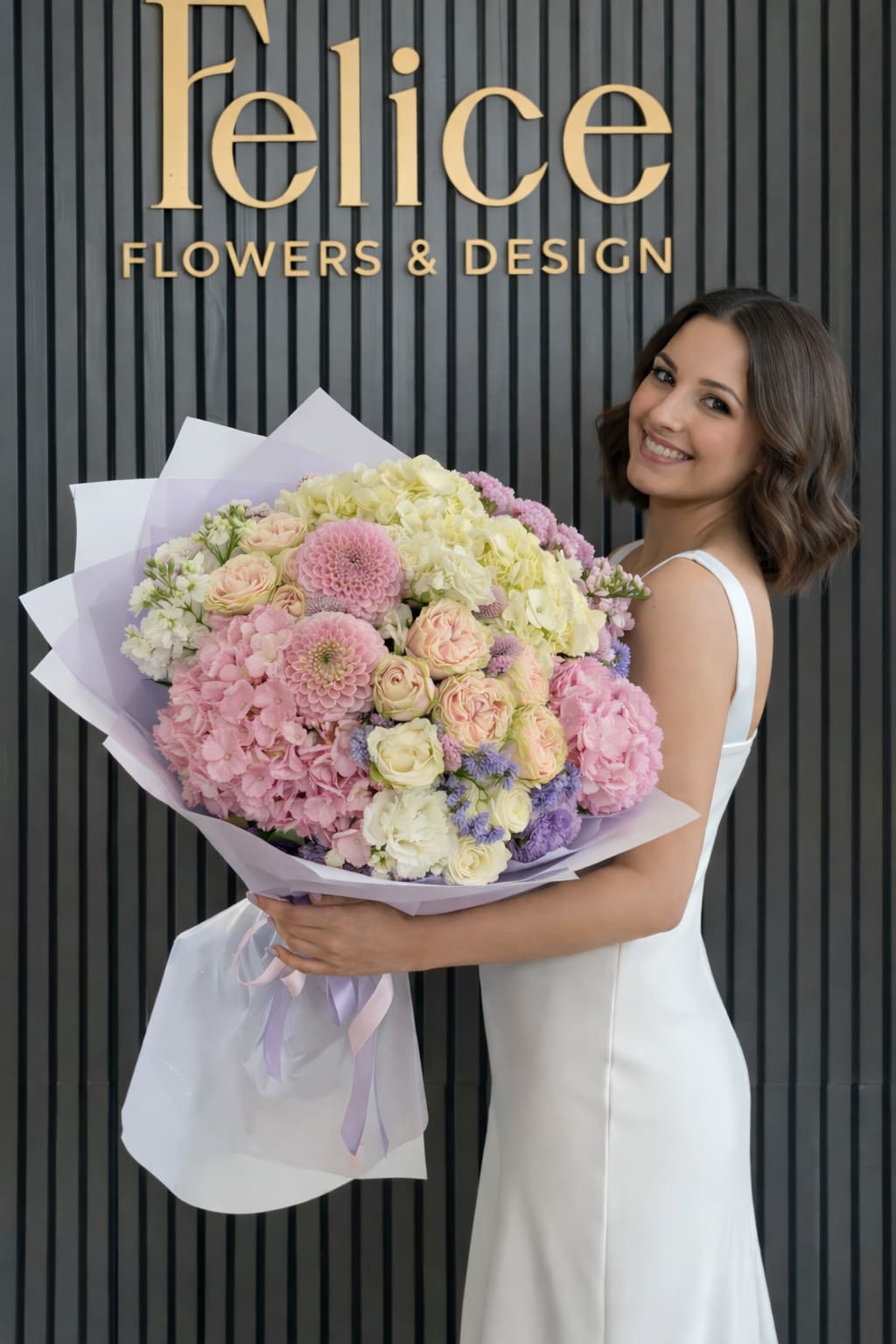 Woman holding a large pastel bouquet of roses, hydrangeas, and dahlias