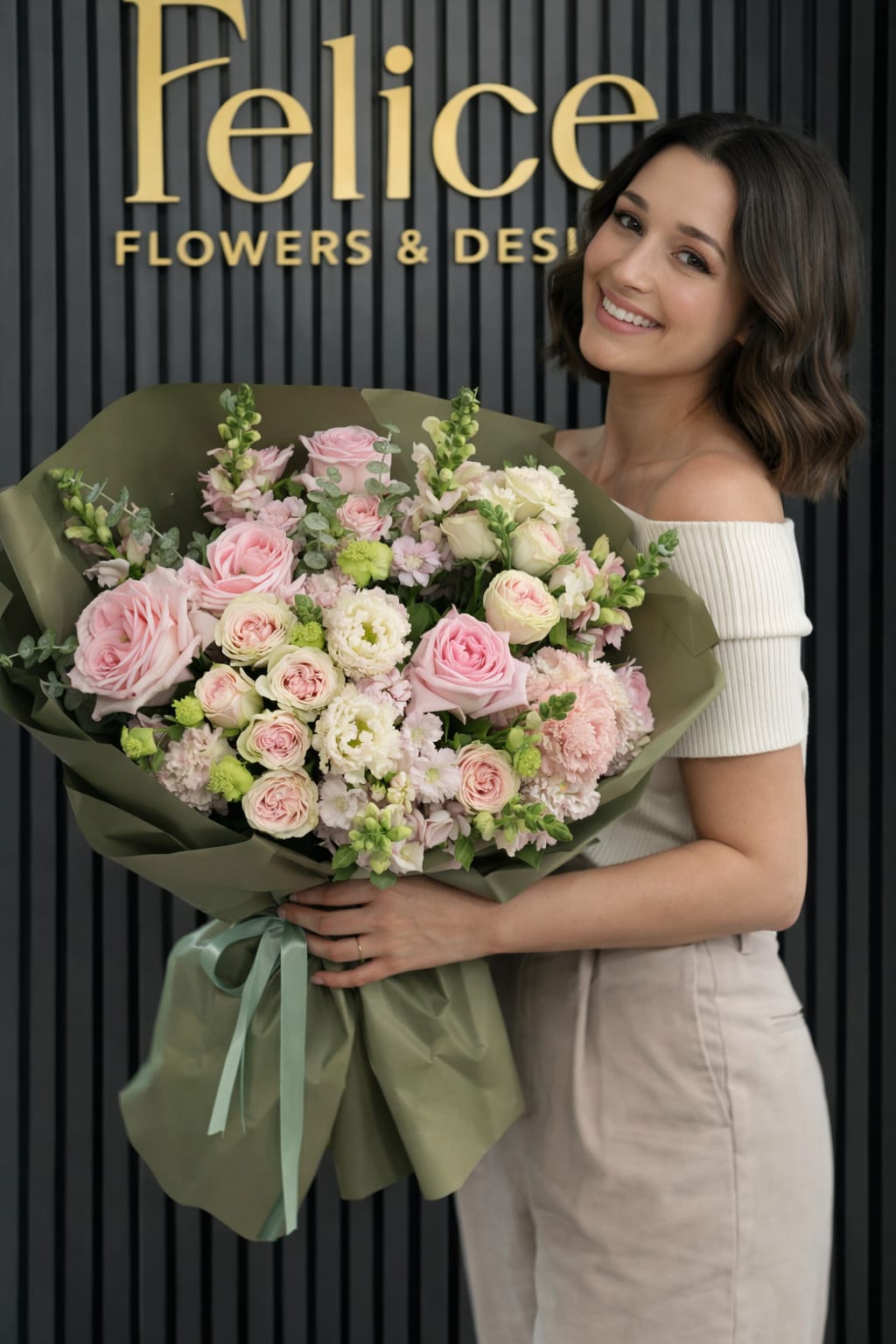 Woman holding a large bouquet of pink and white flowers wrapped in green paper