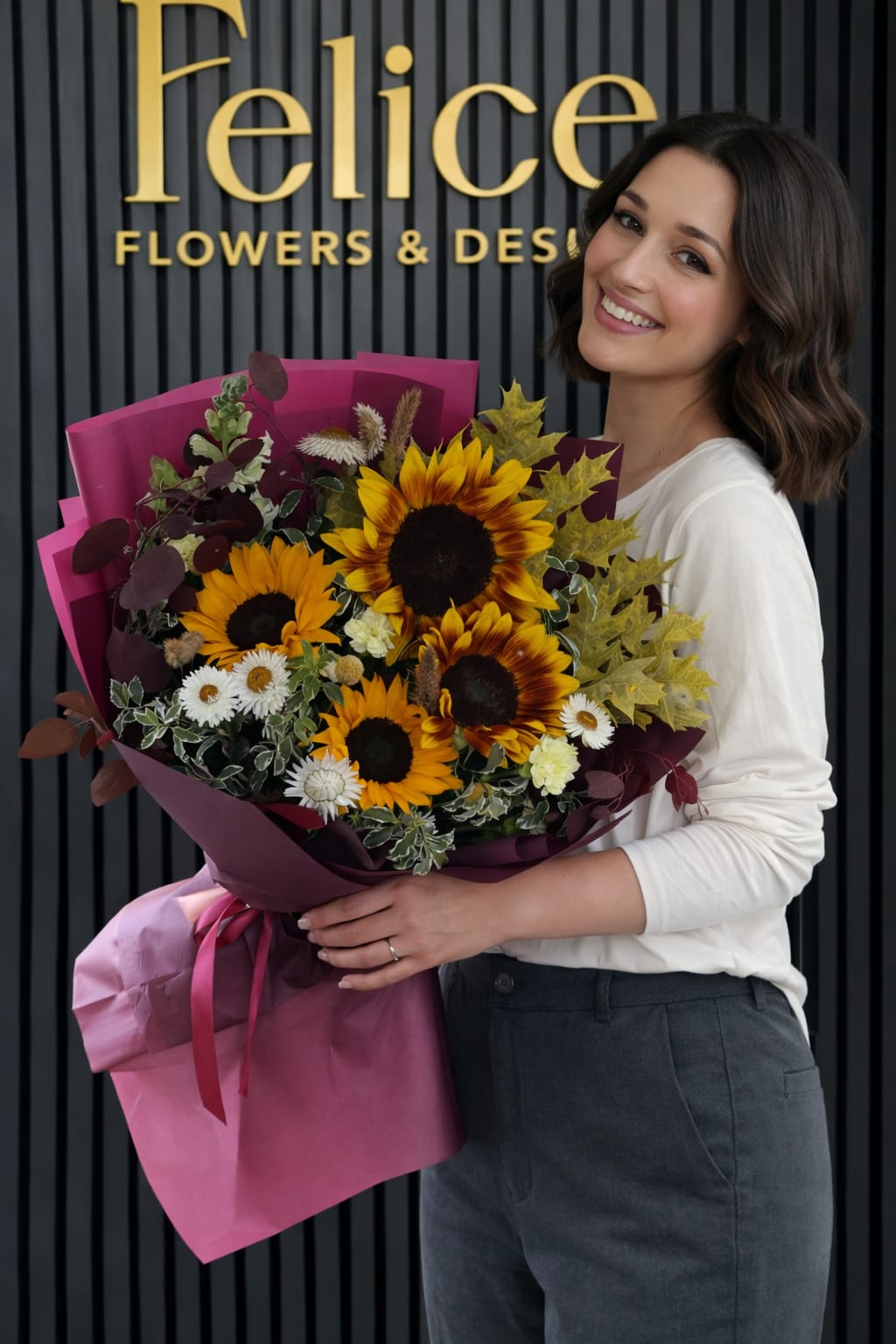 Woman holding a bouquet of sunflowers and small white flowers in pink wrap
