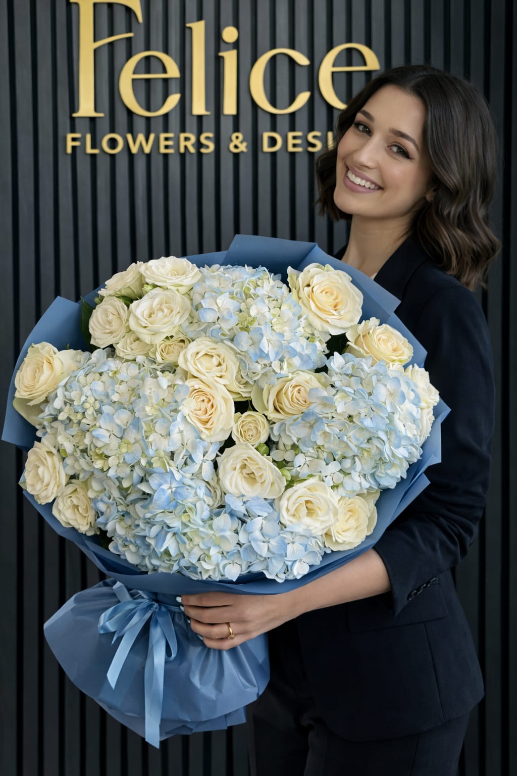 Large bouquet of cream roses and pale blue hydrangeas wrapped in blue paper