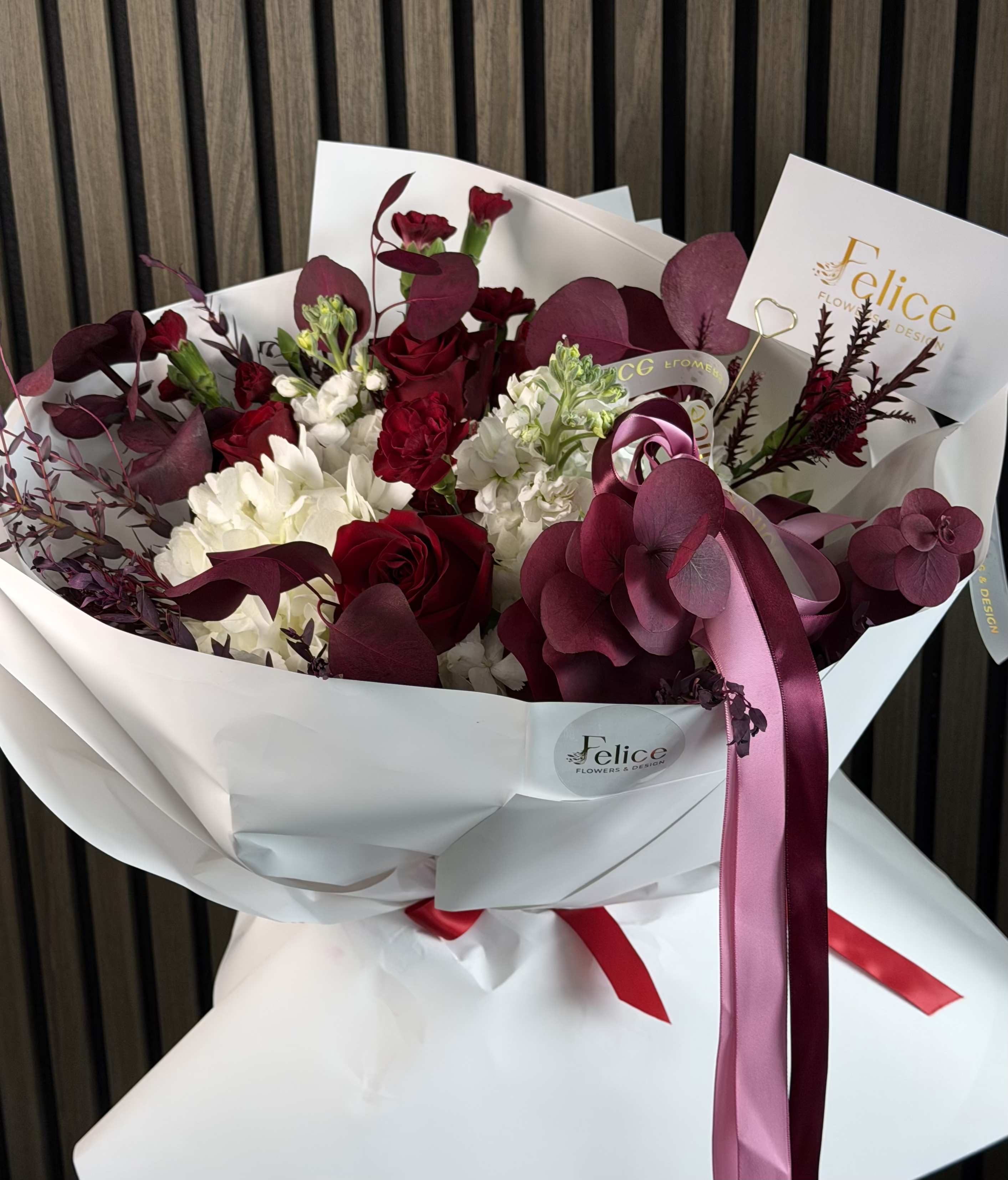 Red &amp; Ivory Luxury Romance Bouquet - A sophisticated red and ivory flower bouquet designed to express deep love, elegance, and timeless romance. This luxurious arrangement features rich crimson roses paired with soft white blooms and accented by burgundy foliage, creating a refined contrast and a bold, high-end aesthetic. Perfect for Valentine’s Day, Anniversary, Love and Romance, Birthday, Thank You, and Special Occasions. Please note: this bouquet may include seasonal flower substitutions depending on availability. While specific flower varieties may vary, the color palette, bouquet size, overall style, and elegant romantic appearance will remain consistent with the photo. Handcrafted with care by Felice Flowers &amp; Design, this bouquet delivers depth, beauty, and a truly premium floral experience.