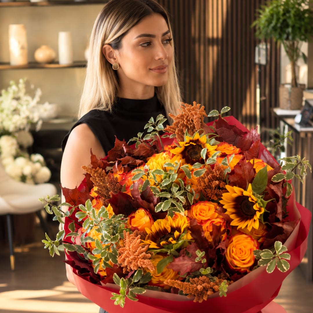Woman holding a large bouquet of sunflowers and orange roses