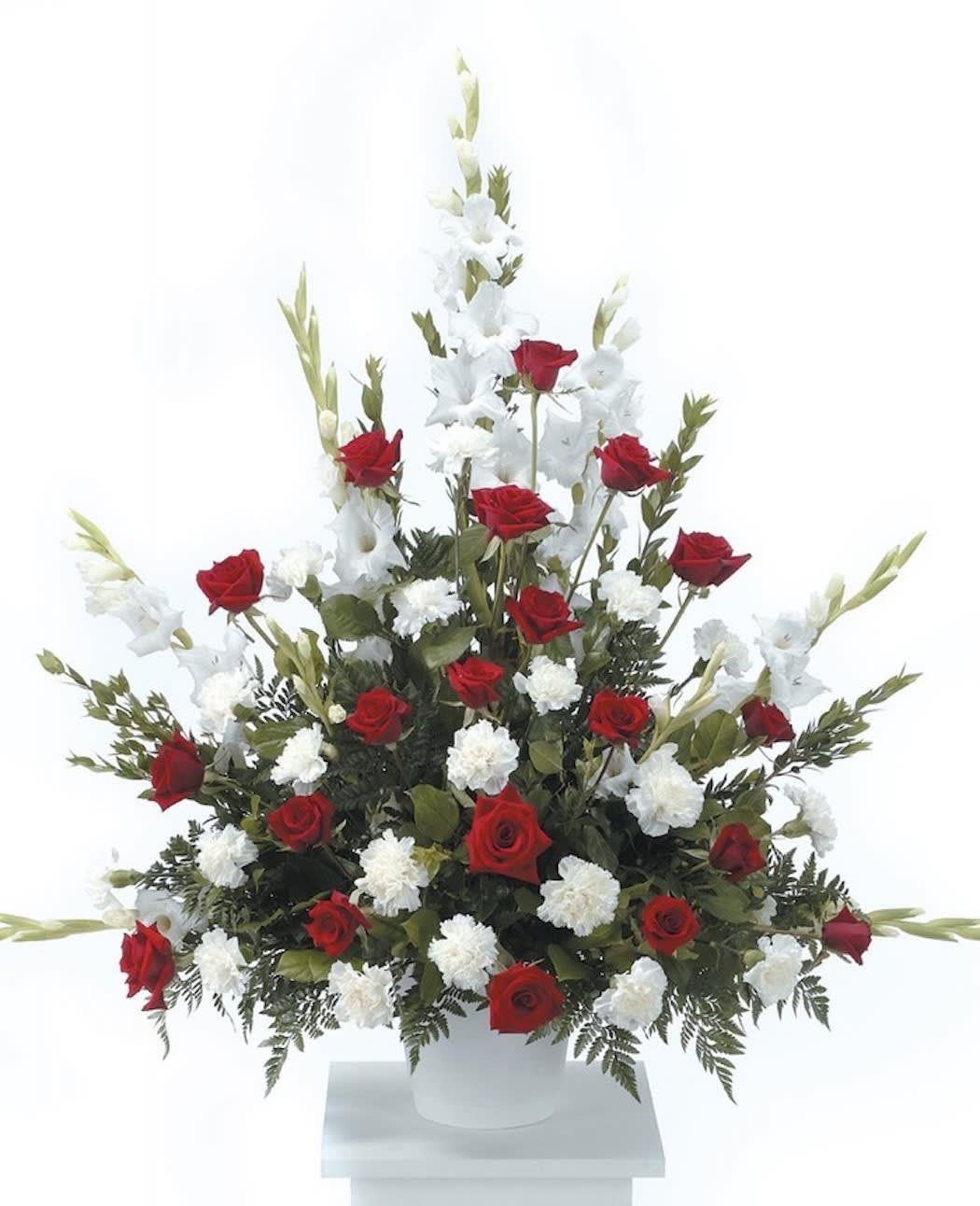 Tall fan-shaped arrangement of red roses and white flowers in a white urn container