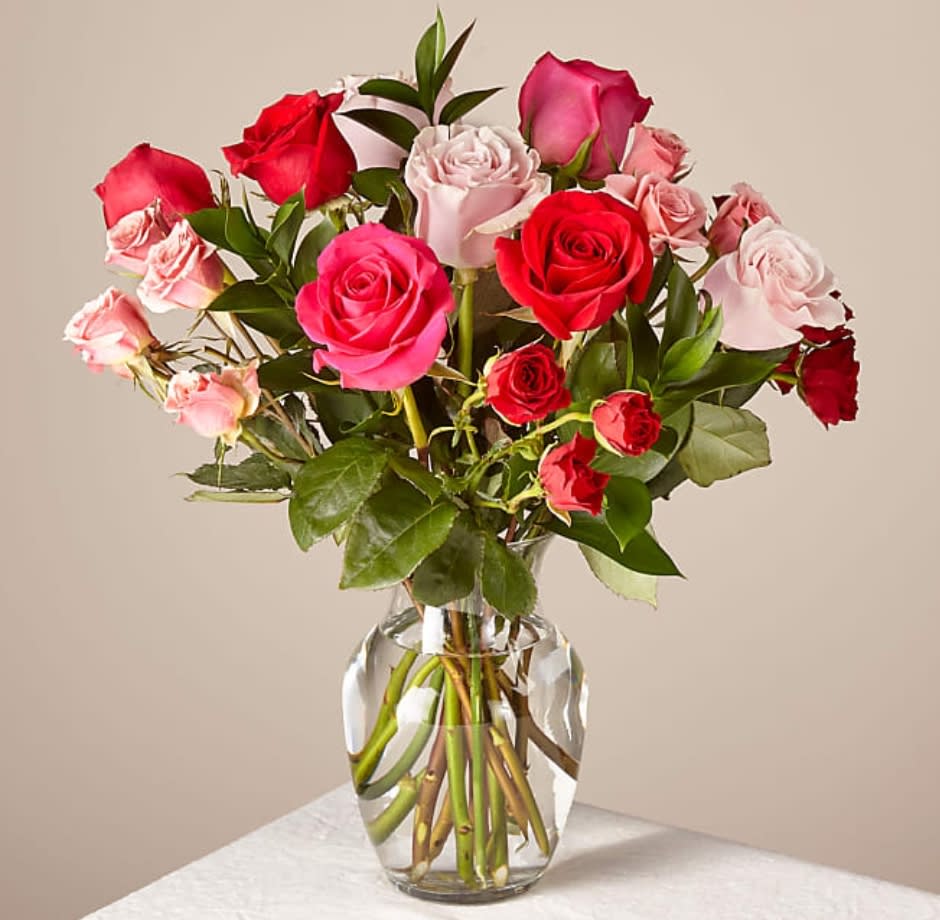 Bouquet of red and pink roses arranged in a clear glass vase