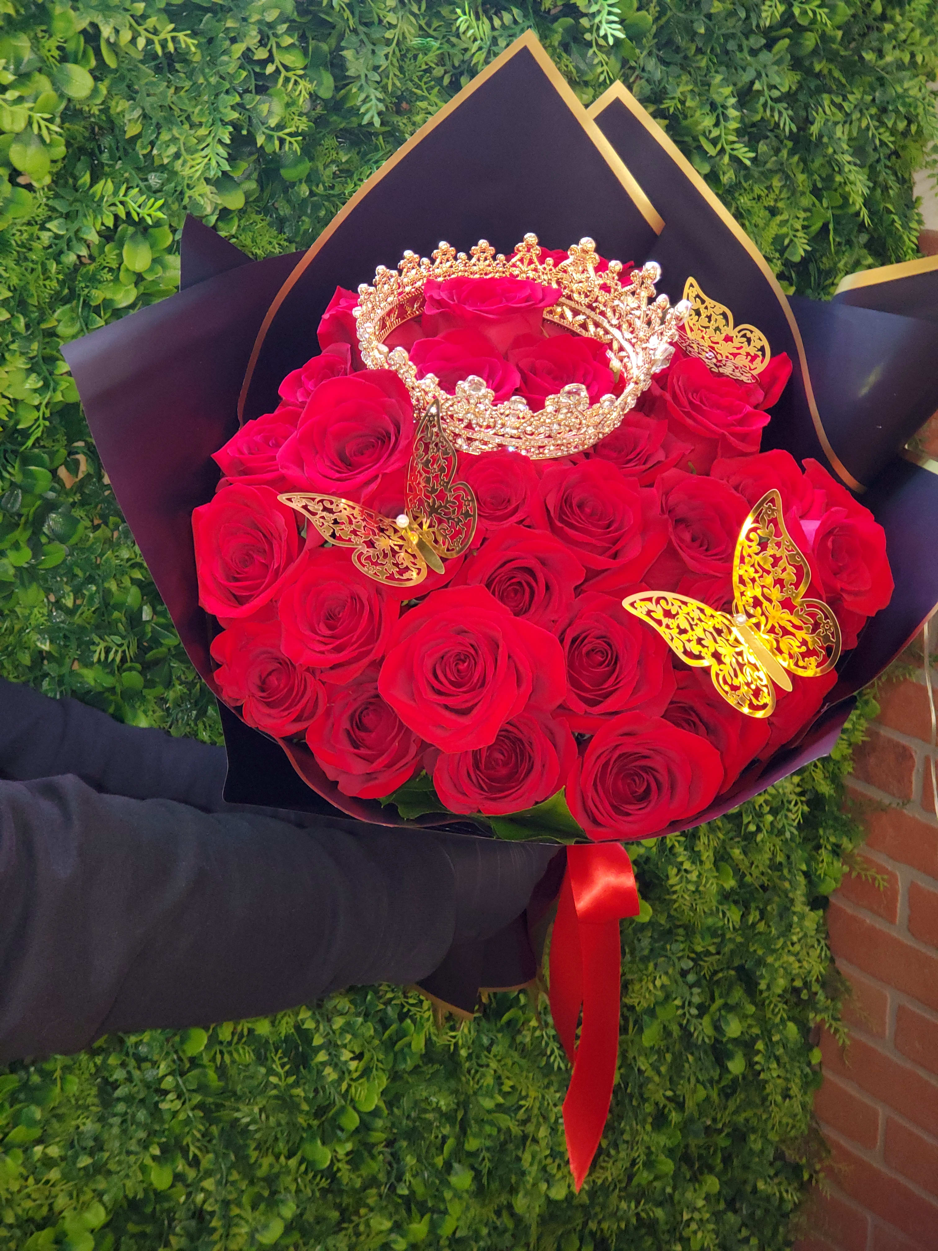 Bouquet of red roses with a gold crown and butterflies in black wrapping