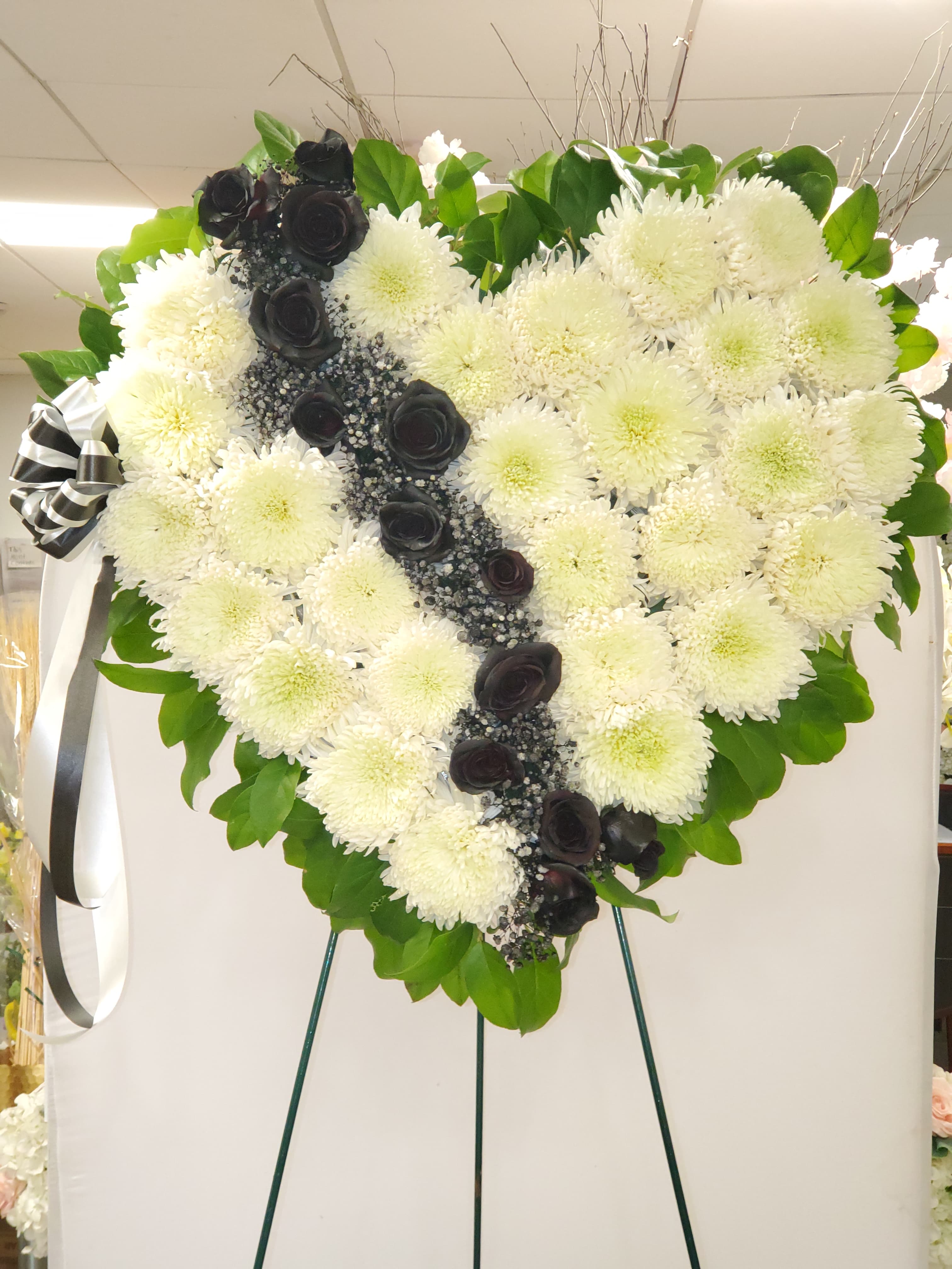 Heart-shaped white chrysanthemum wreath with black roses and ribbon