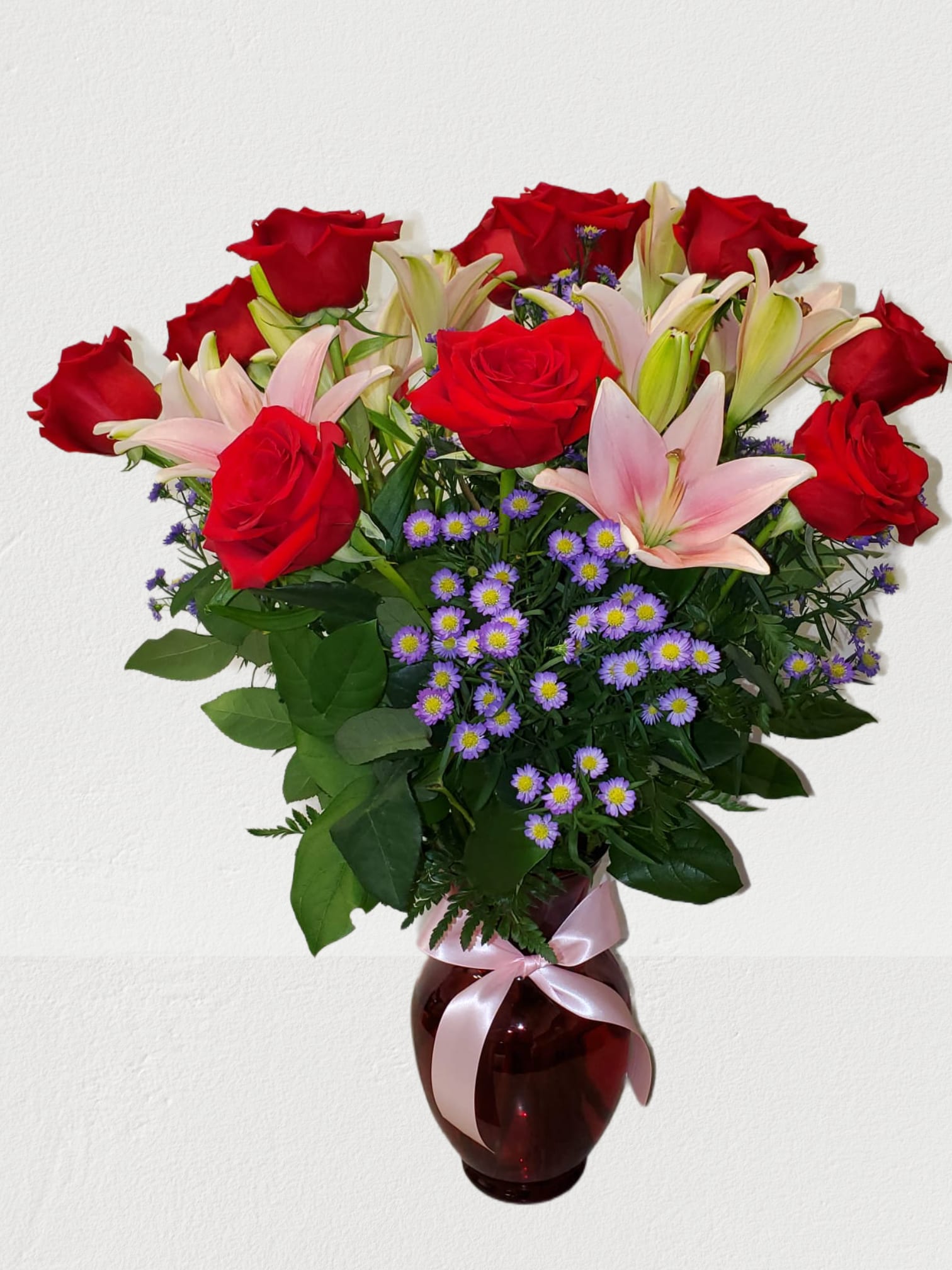 Red roses and pink lilies in a vase with a ribbon