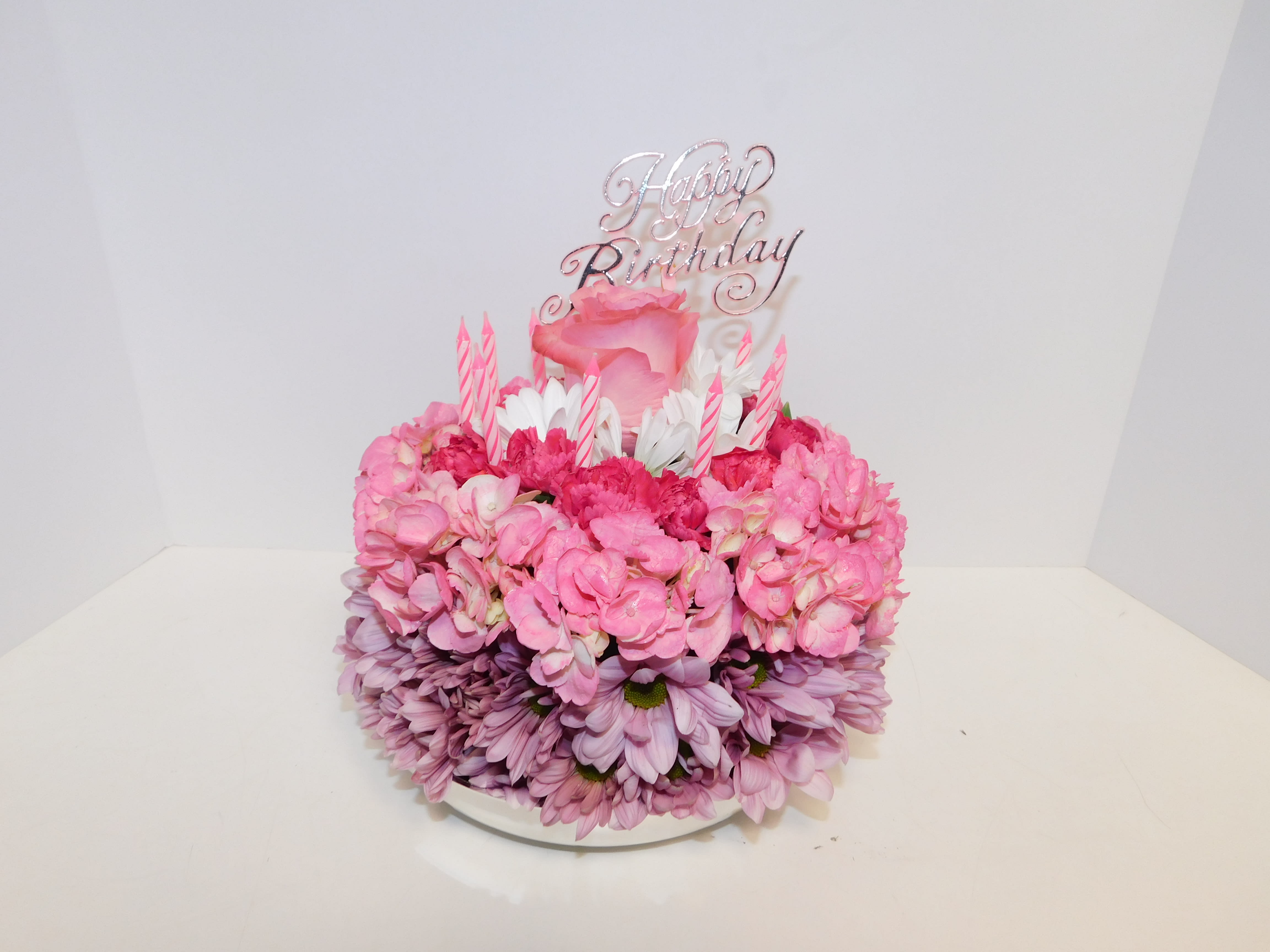 Pink floral birthday cake with candles and a Happy Birthday topper