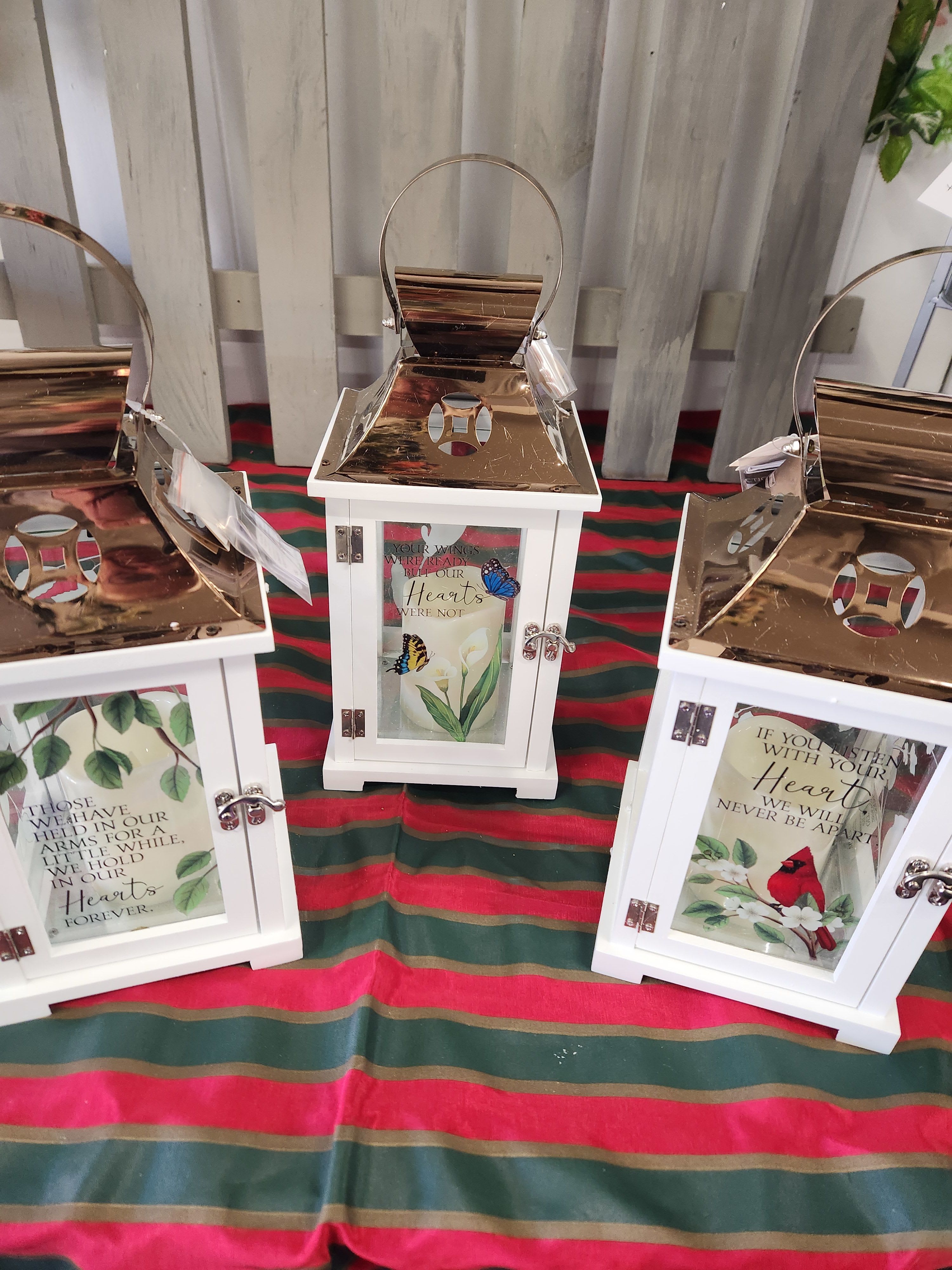 Three white lanterns with memorial messages and butterfly designs