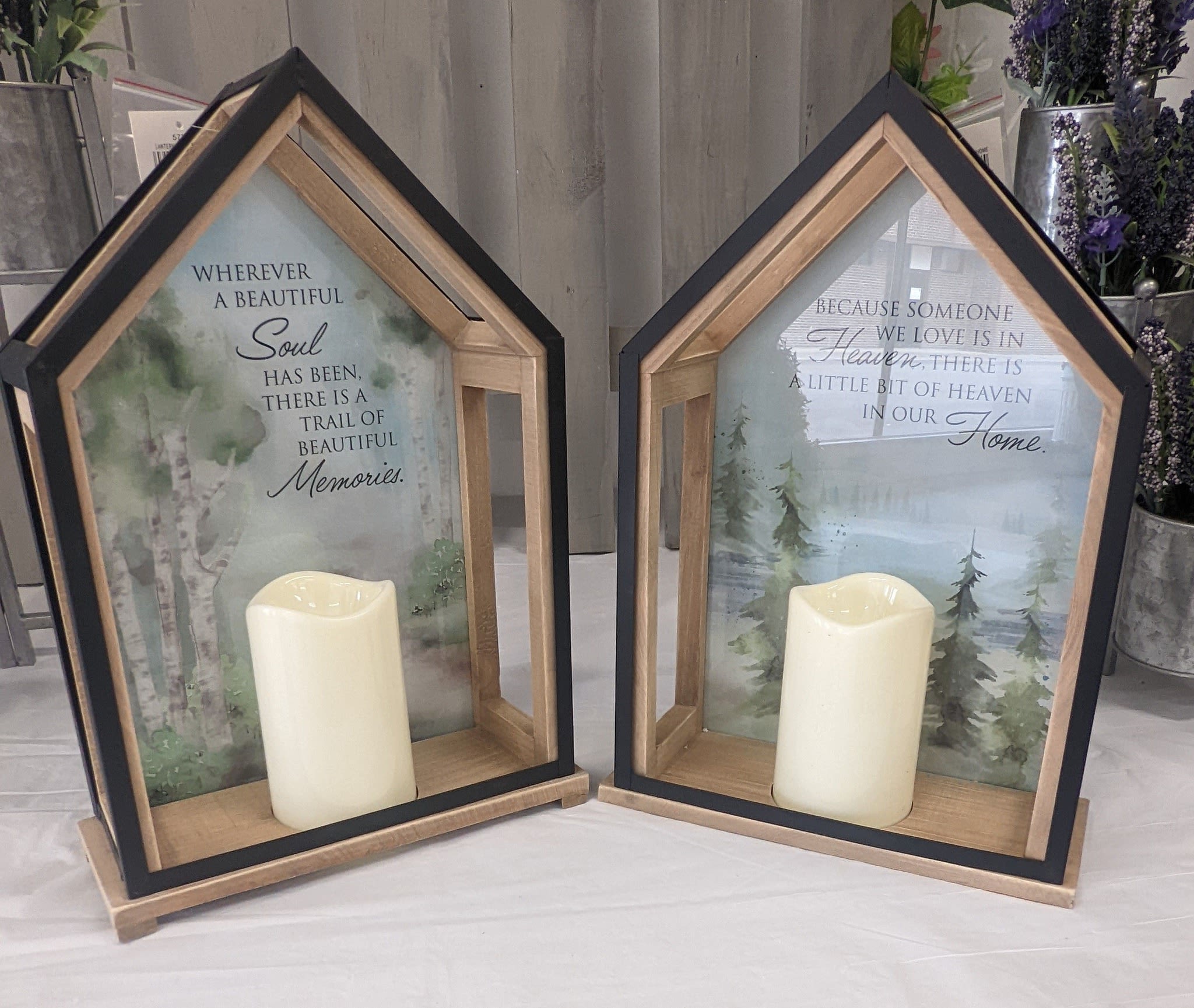 Two house-shaped memorial lanterns with candles and printed sympathy messages