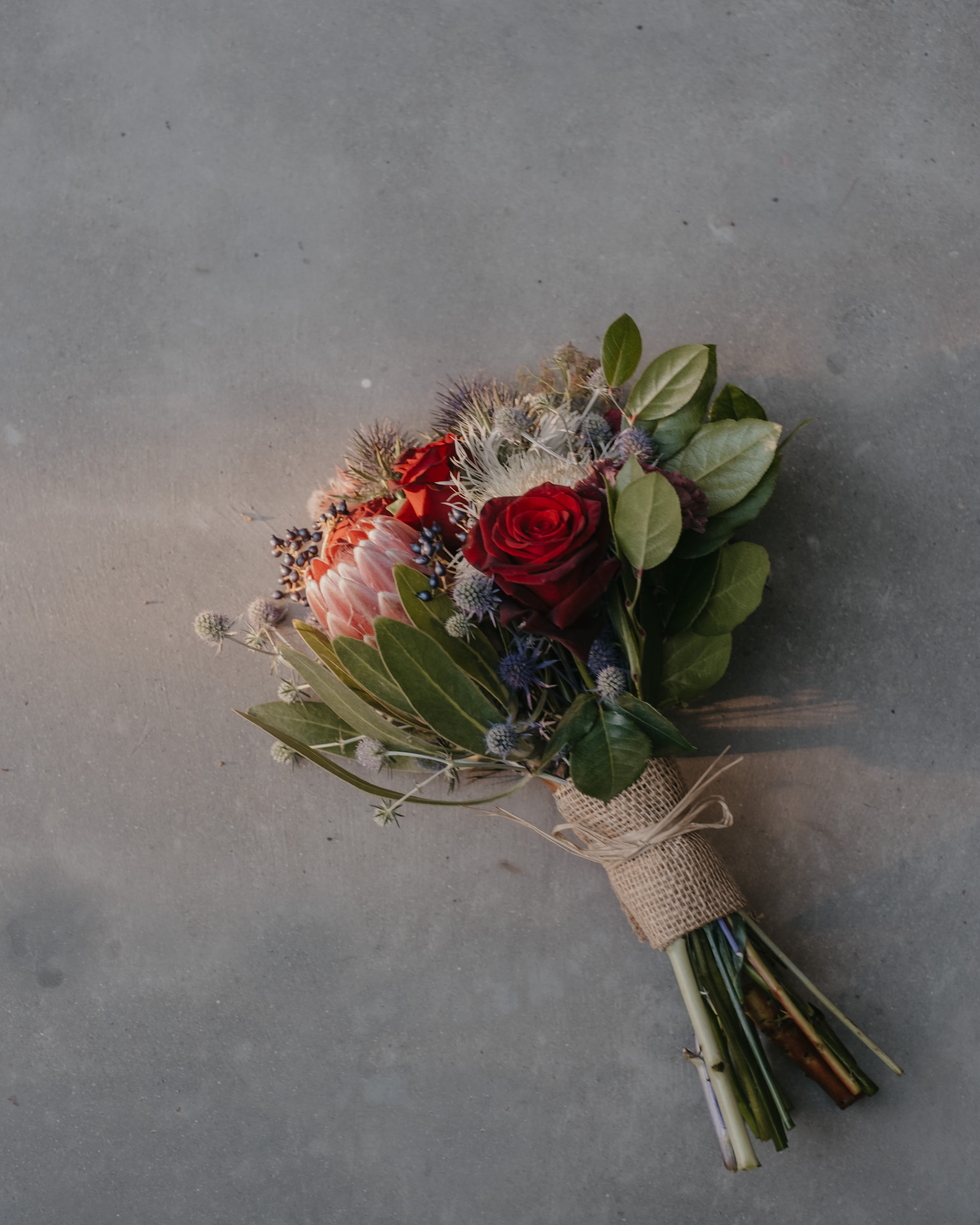 Hand-tied bouquet with red roses and a pink protea