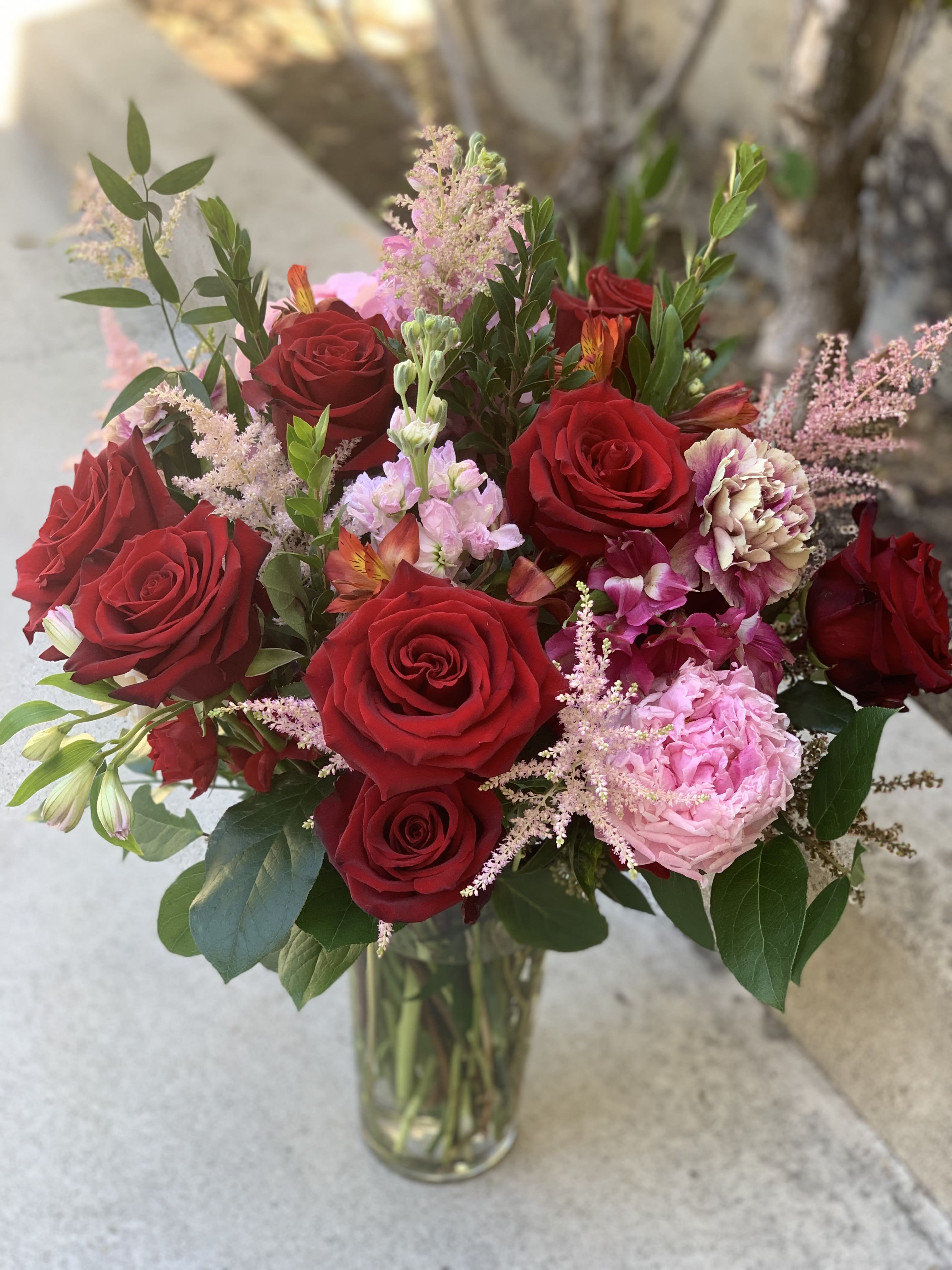 Bouquet of red roses and pink flowers in a clear glass vase