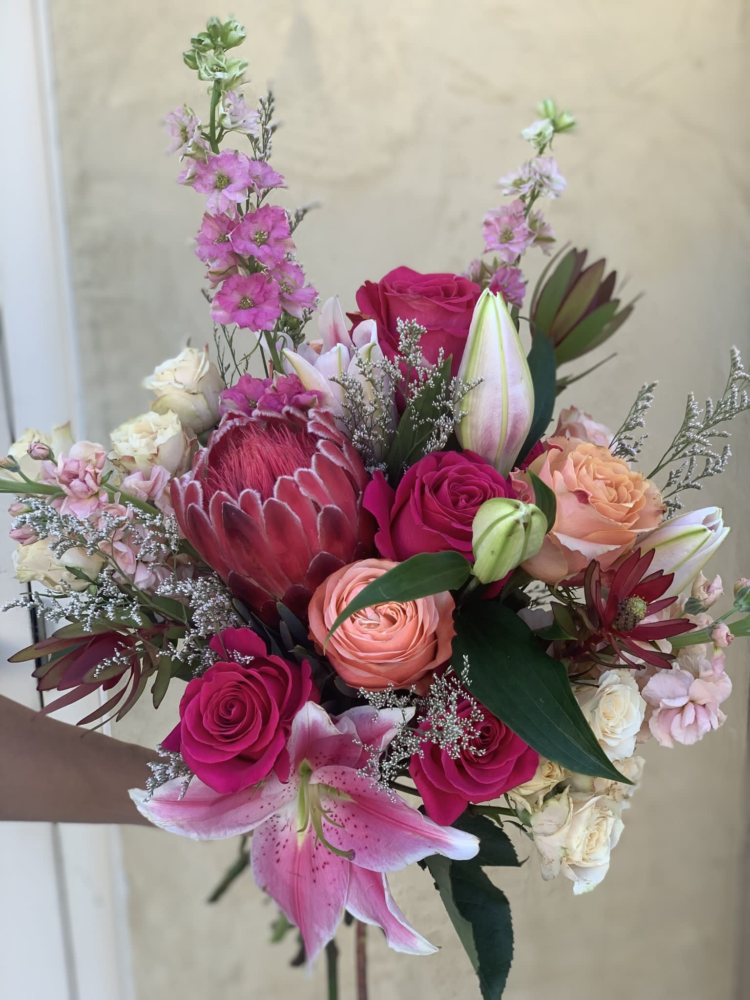 Hand-tied bouquet with pink roses, lilies, and a protea
