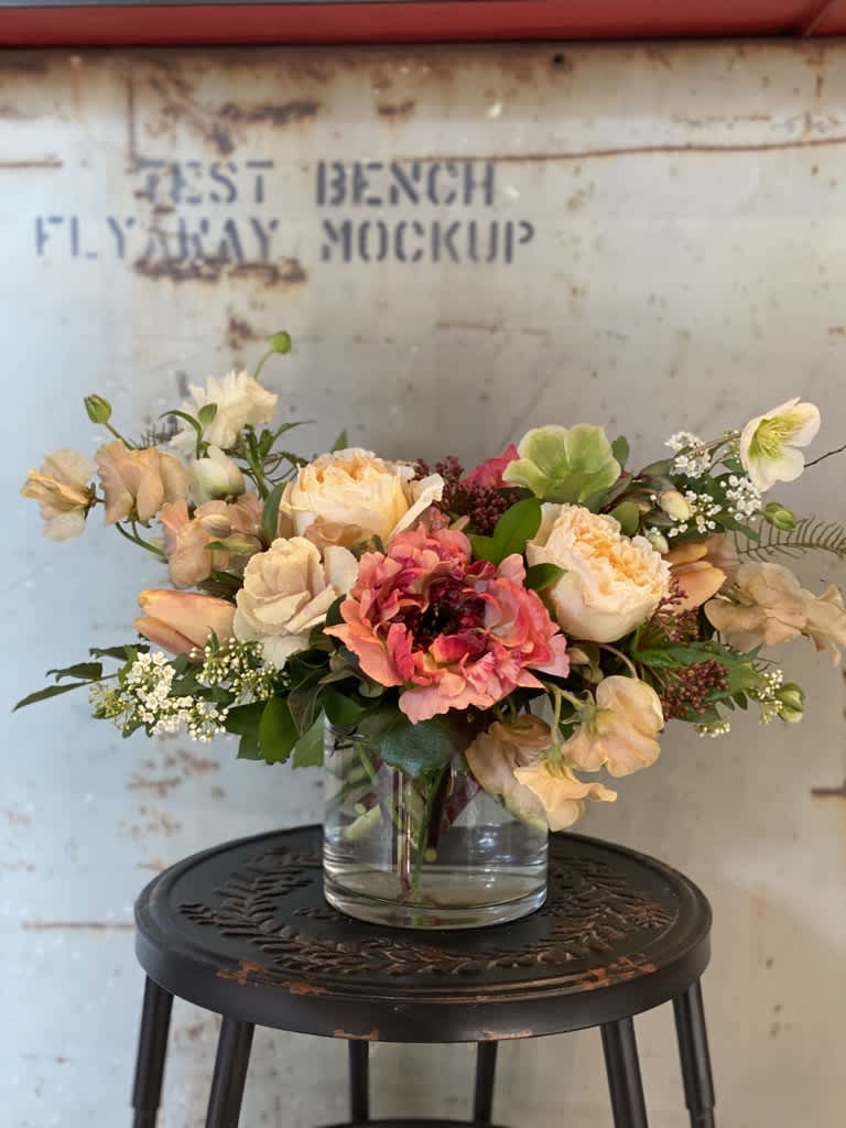 Mixed bouquet of peach, pink, and white flowers in a clear glass vase