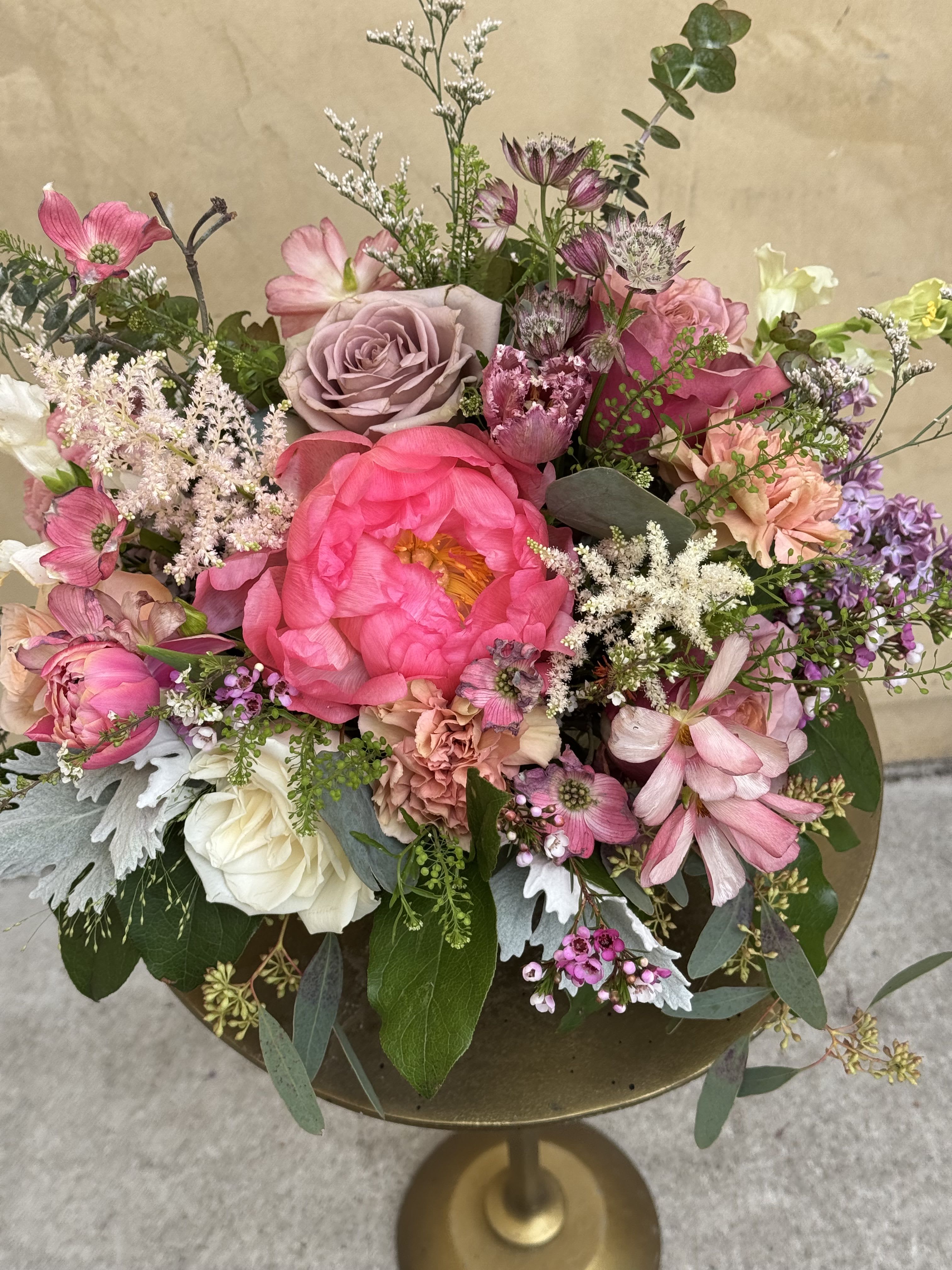 Mixed pink and white floral arrangement in a gold pedestal vase