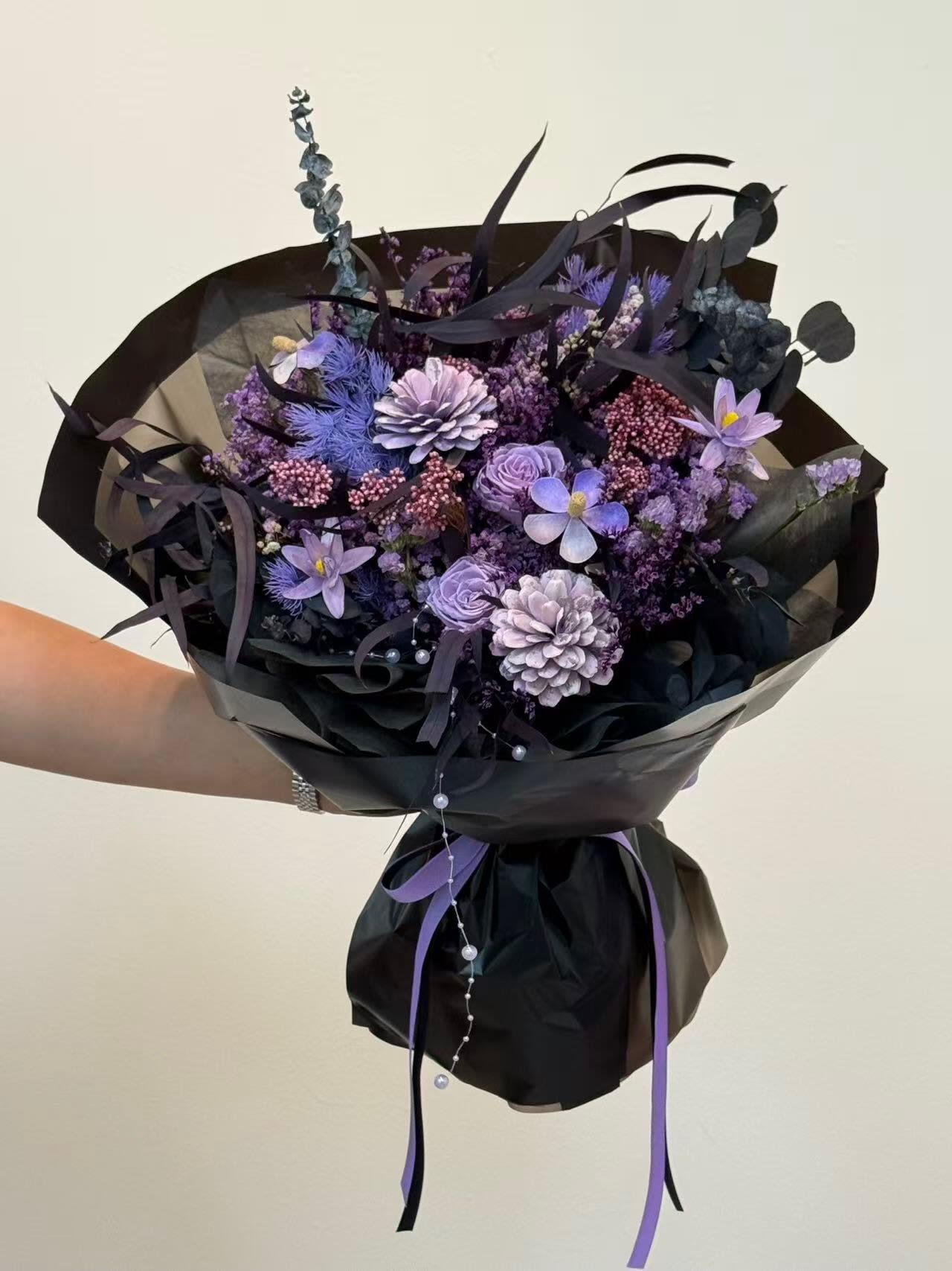 Purple bouquet wrapped in black paper with ribbon