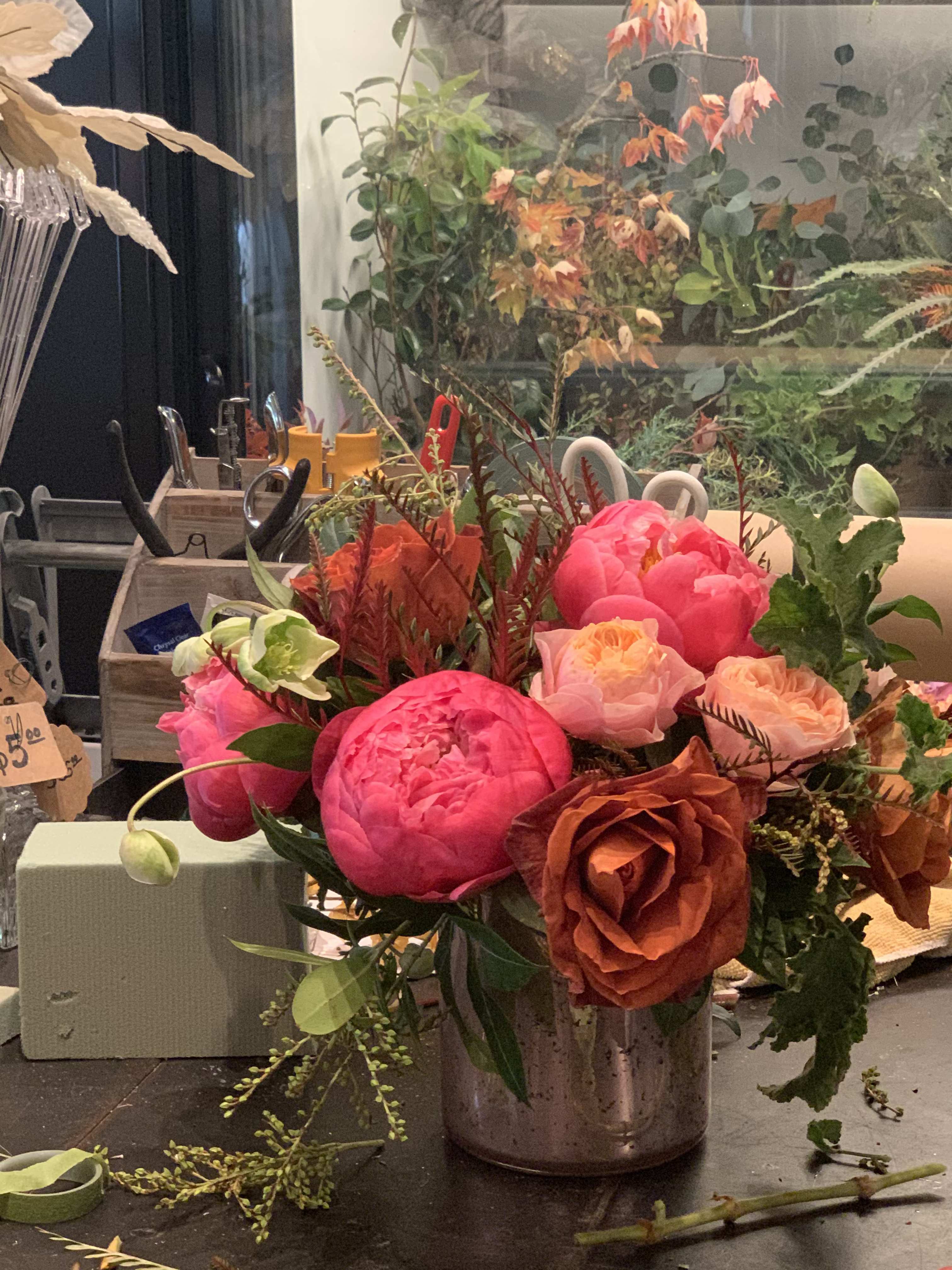 Bright pink and peach peonies and roses in a metal vase
