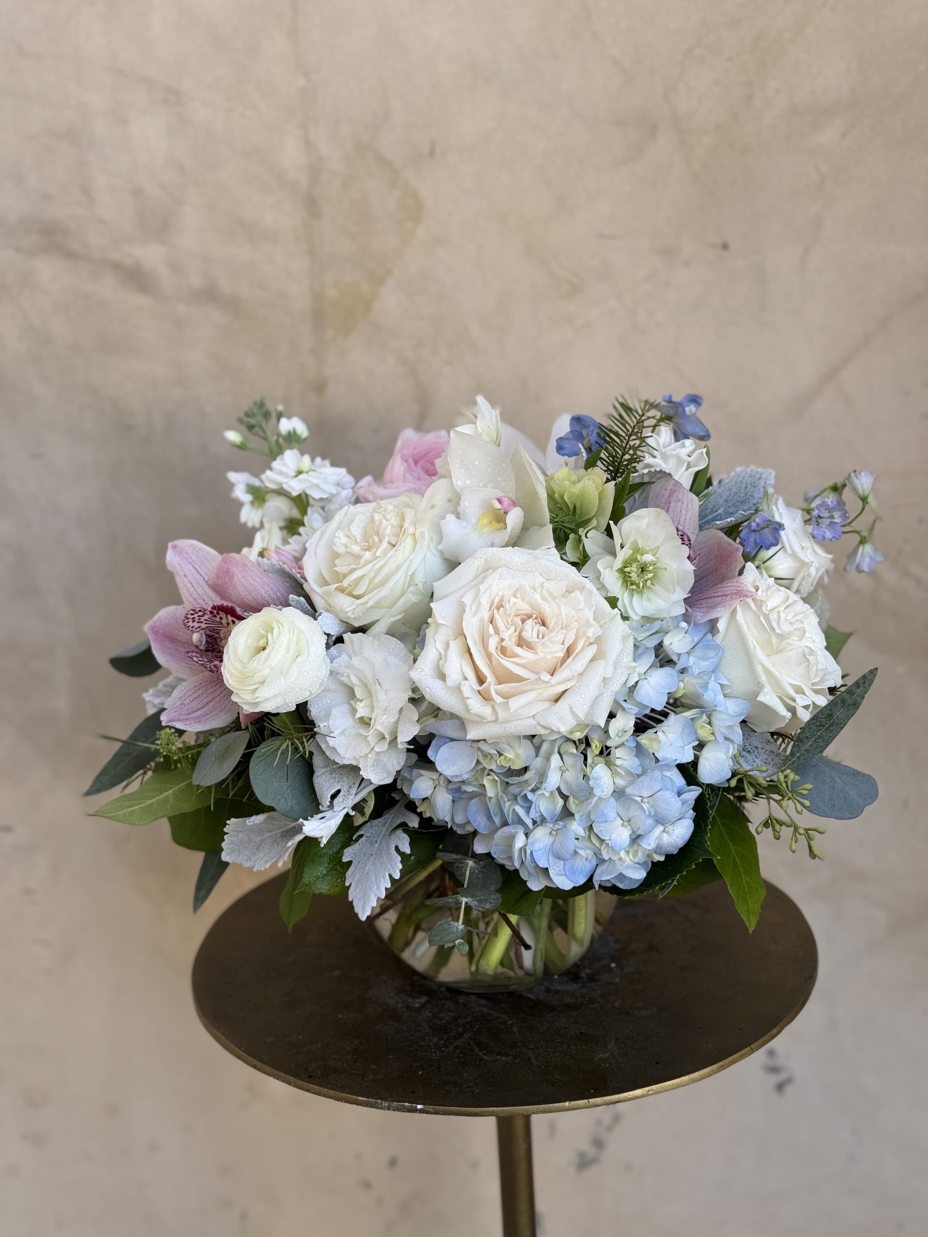 Pastel bouquet of roses, hydrangeas, and orchids in a glass vase