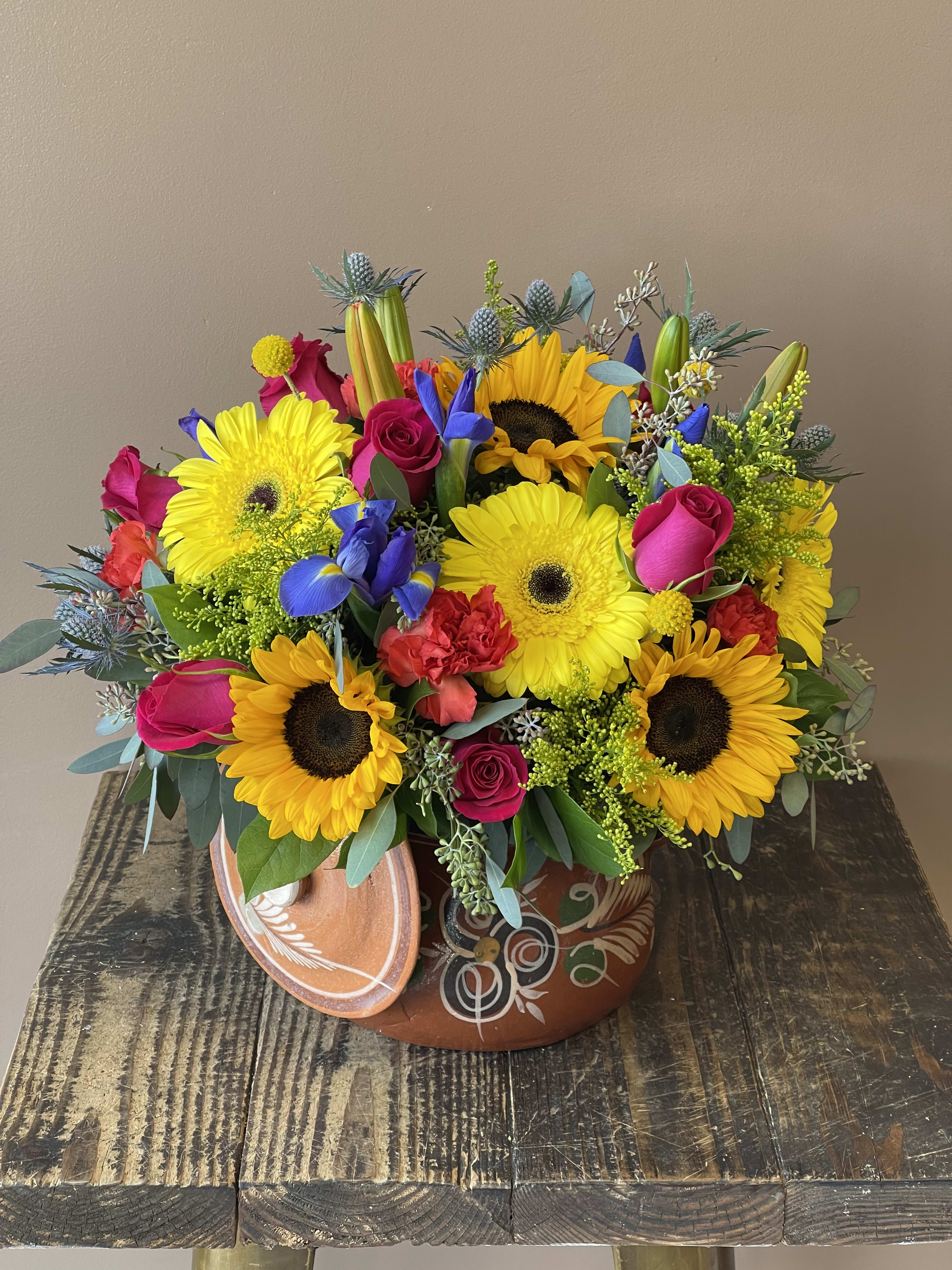 Bright mixed bouquet with sunflowers, gerbera daisies, roses, and irises in a decorative pot