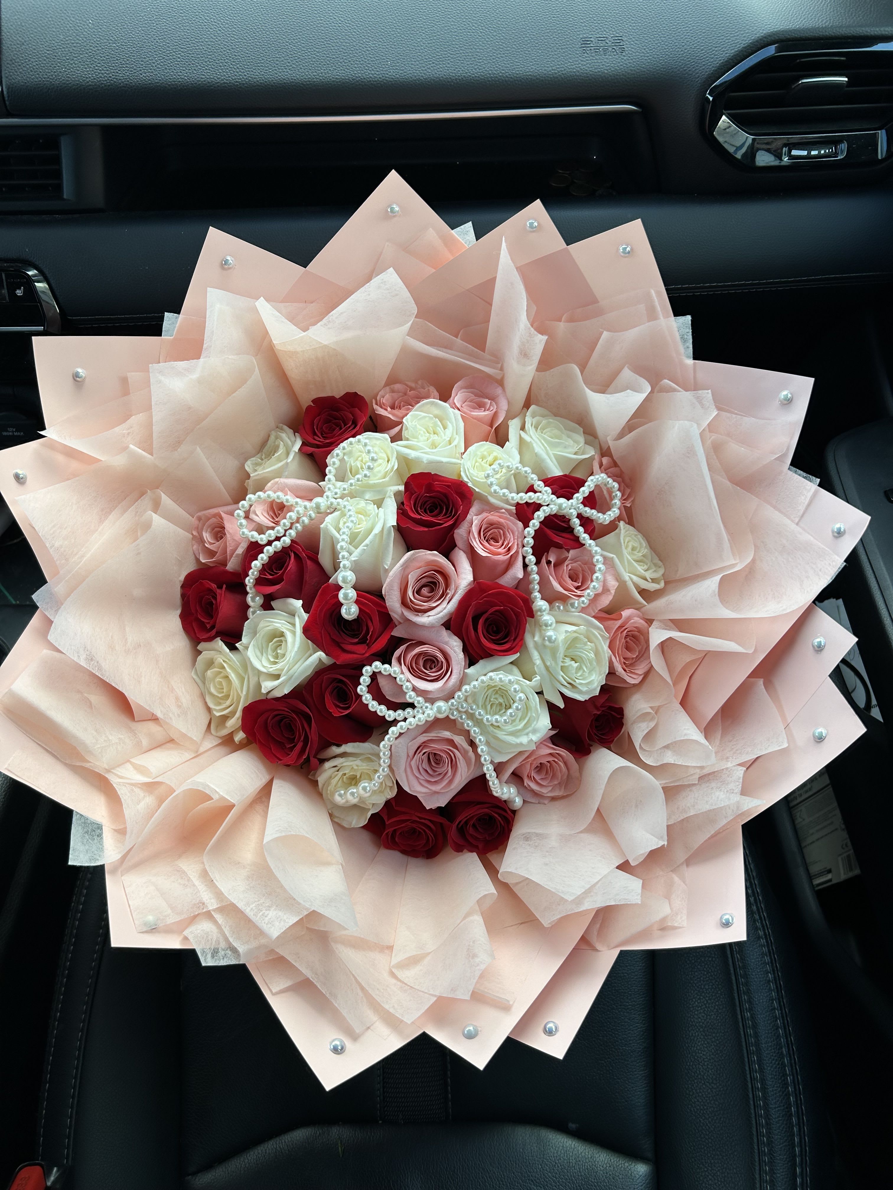 Bouquet of red, pink, and white roses wrapped in pale blush paper
