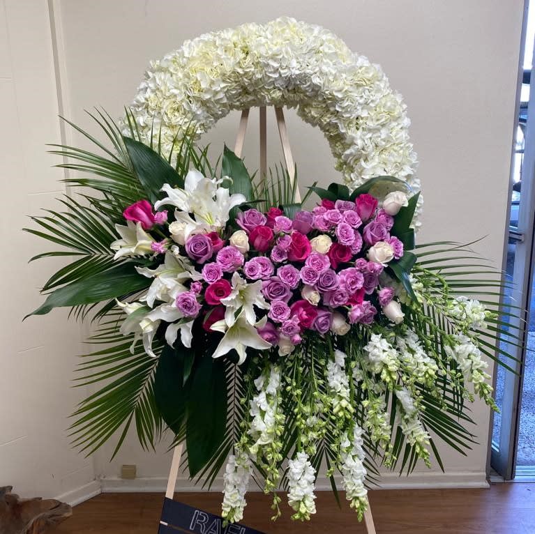 Large floral standing spray with pink and white roses and lilies on an easel