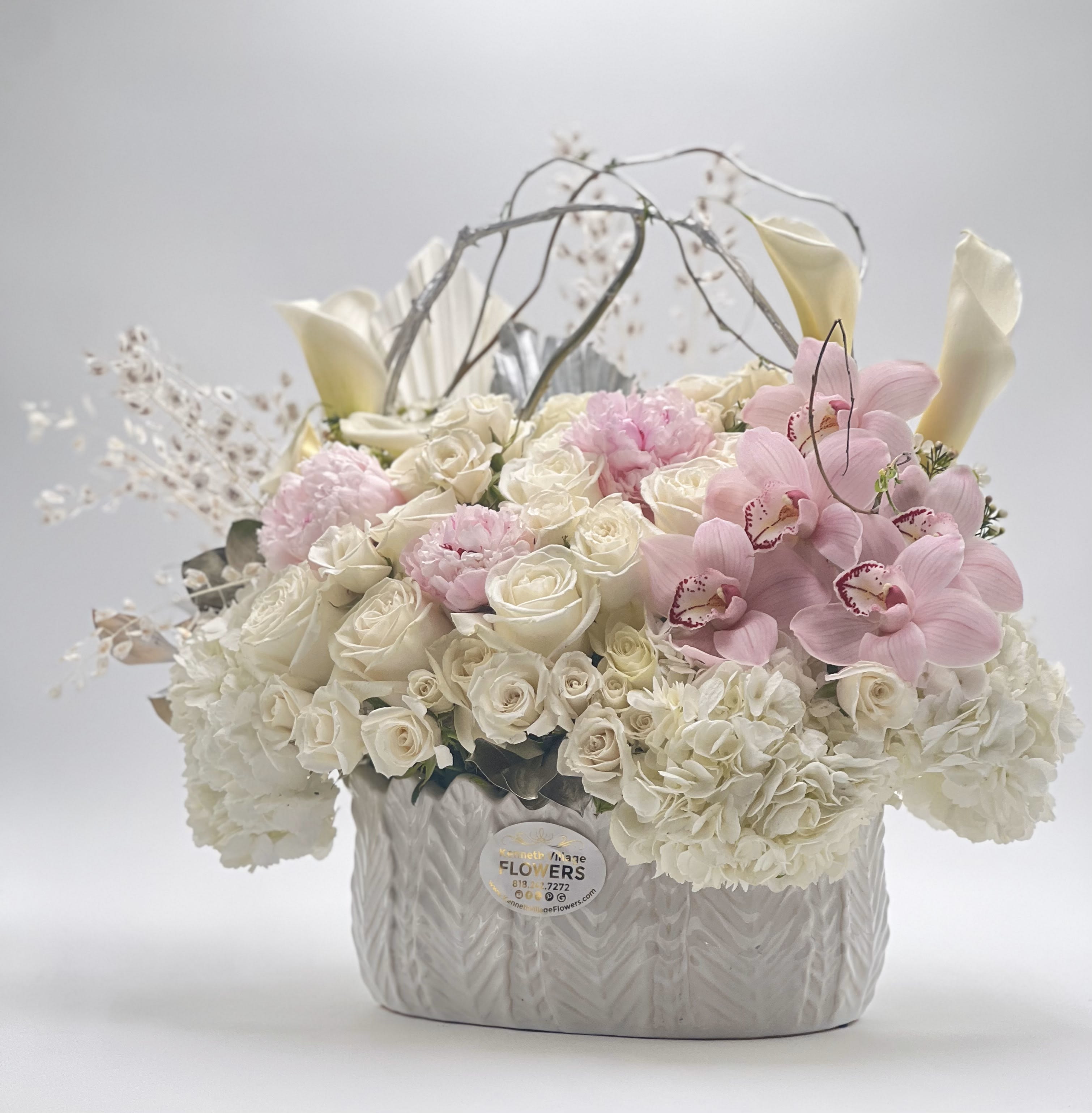 White roses and pink orchids arranged in a textured silver vase