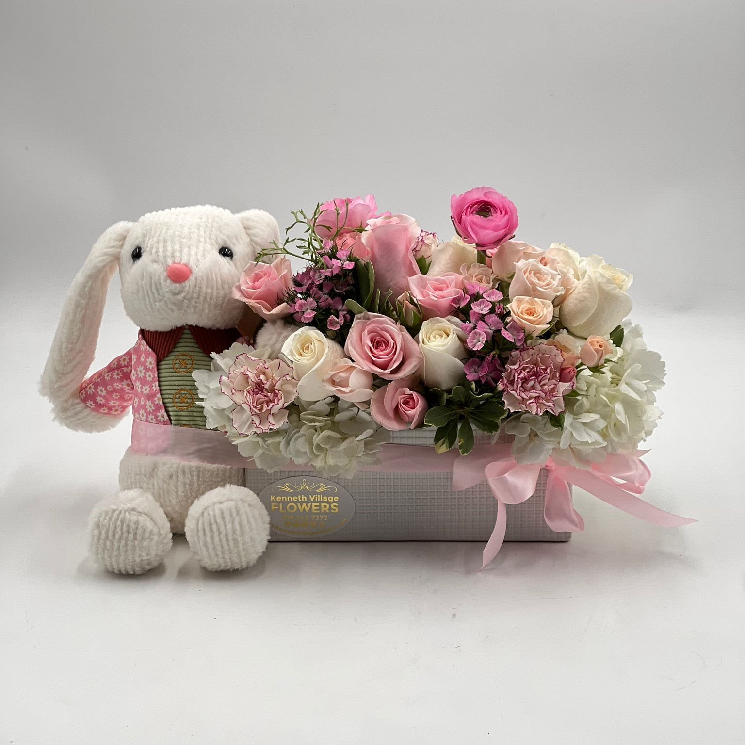 Pink and white flower arrangement with a knitted bunny plush in a box