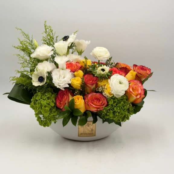 Sunrise Elegance - Bright, graceful, and full of natural charm, Sunrise Elegance captures the warmth of a beautiful morning in bloom. This handcrafted arrangement features a stunning blend of premium roses, ranunculus, anemones, lisianthus, hydrangeas, and lush seasonal greenery, artfully arranged in a contemporary ceramic bowl. The harmonious mix of warm coral, golden yellow, crisp white, and vibrant green creates a sophisticated design that is perfect for birthdays, anniversaries, congratulations, thank-you gifts, housewarmings, or simply brightening someone's day with fresh floral beauty.