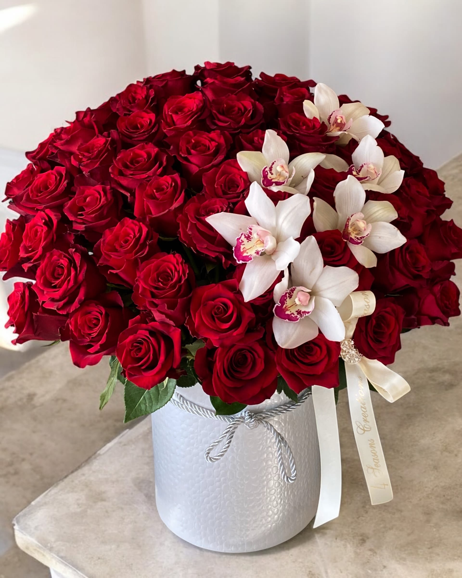 Red roses and white orchids arranged in a white hatbox