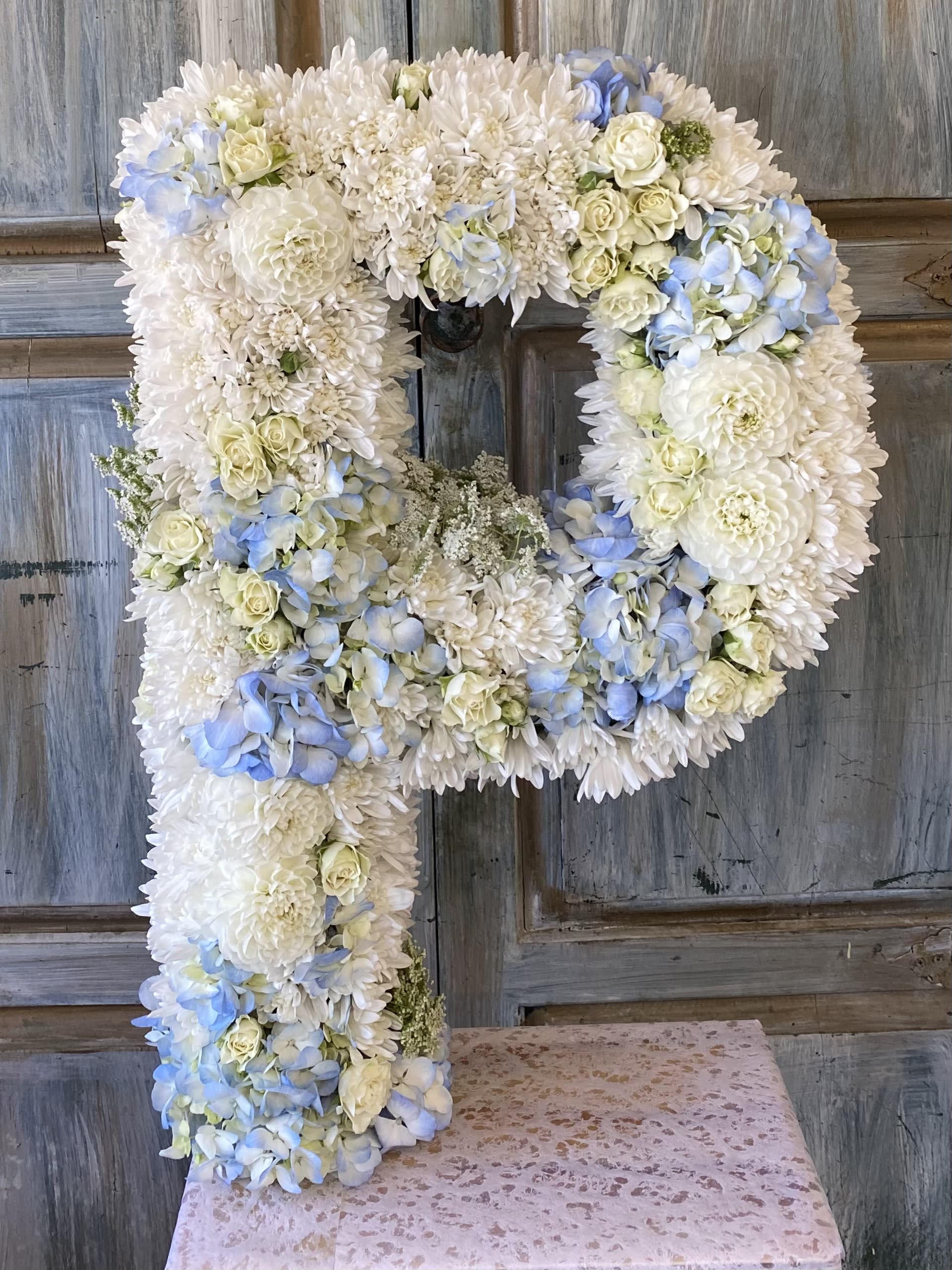 Large floral letter P made of white and pale blue flowers