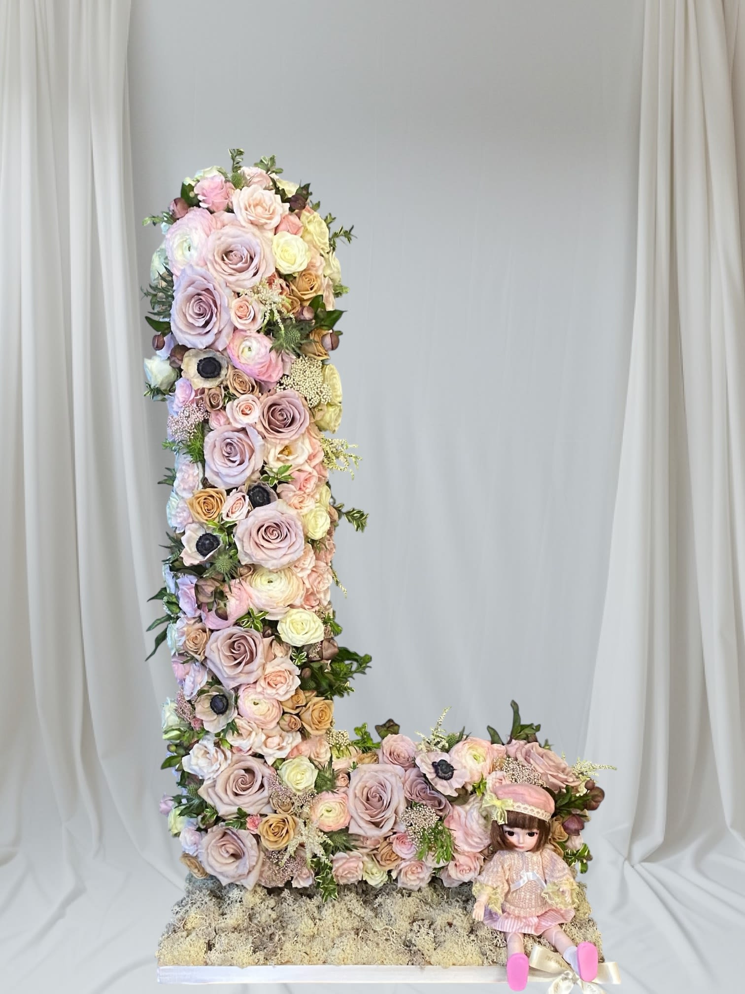 Tall floral letter L with pastel roses and a doll at the base
