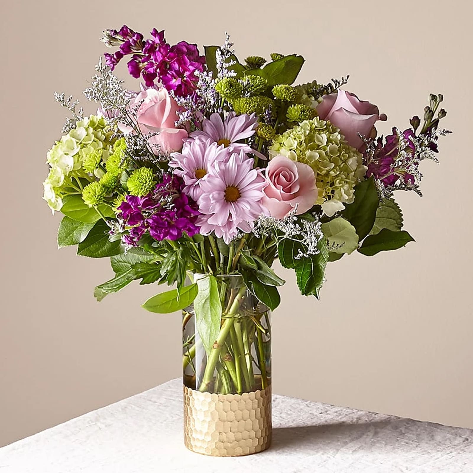 Mixed pink and purple flowers arranged in a clear glass vase