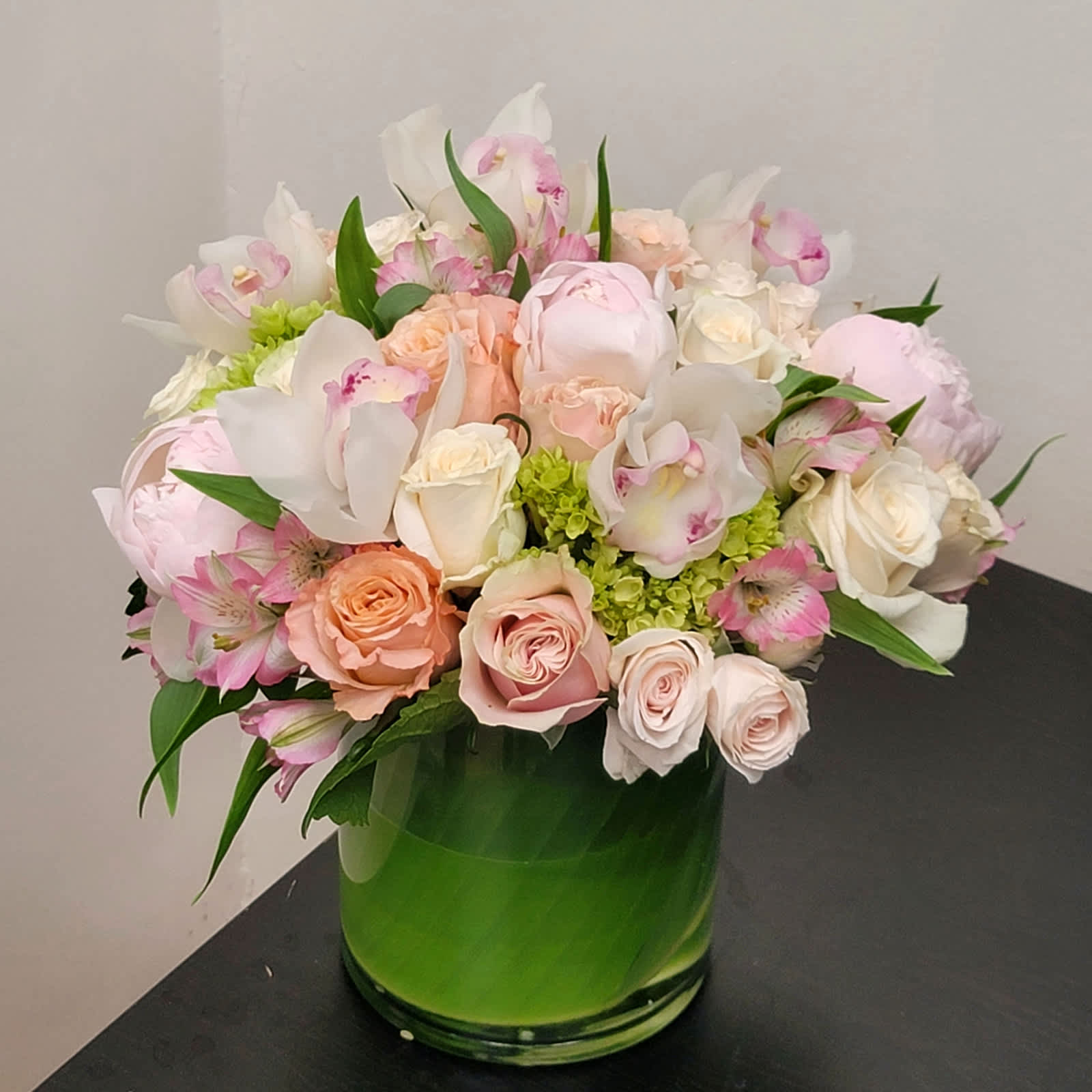 Bouquet of pale pink and white flowers in a green glass vase